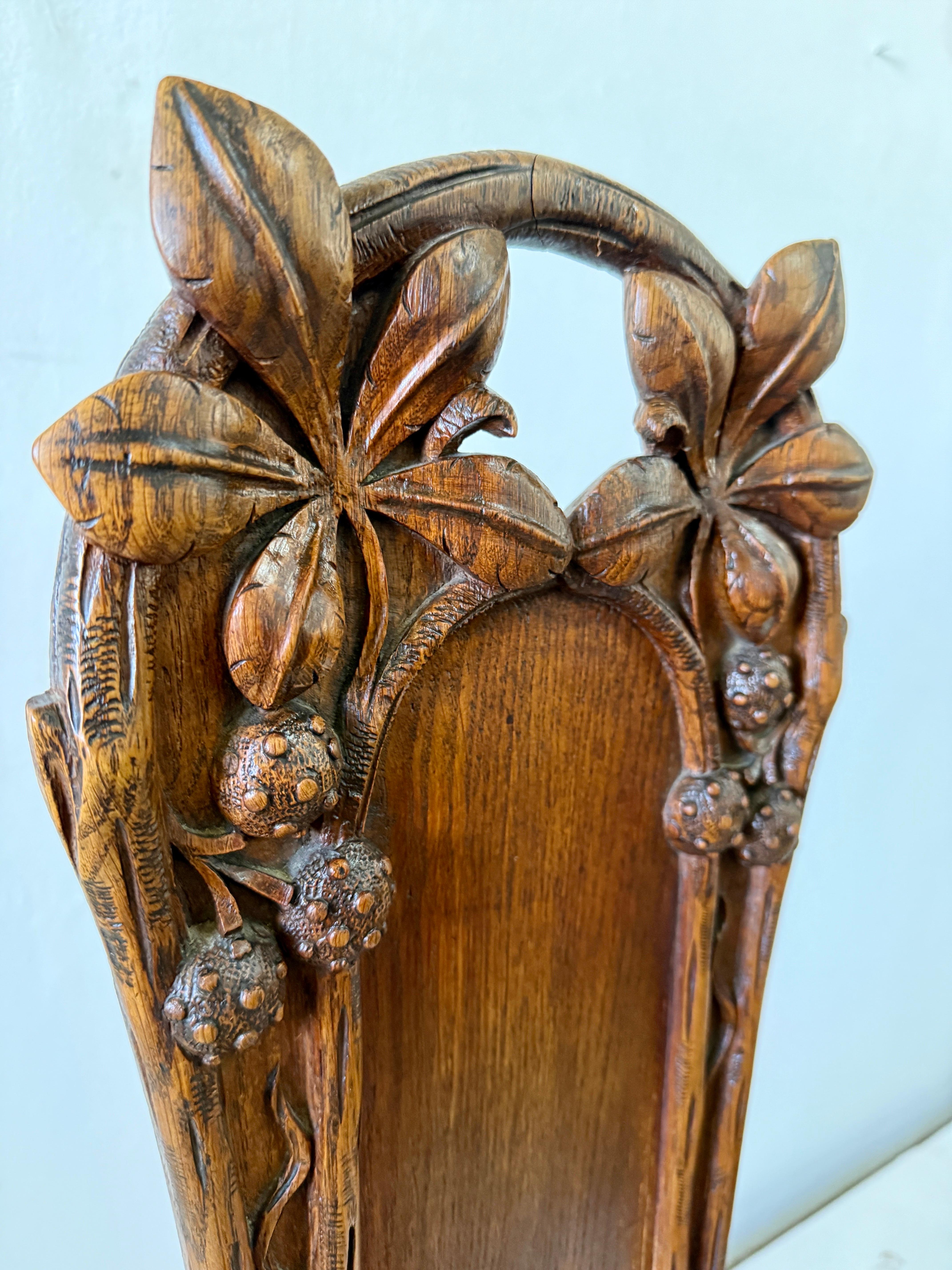 Maison Antoine Bastet of Lyon, France (Labelled to underside of both chairs) created these exquisite hand carved oak Hall chairs with wonderful reliefs of chestnuts, foliage and bamboo shoots.  The richness of the aged oak and years of patina