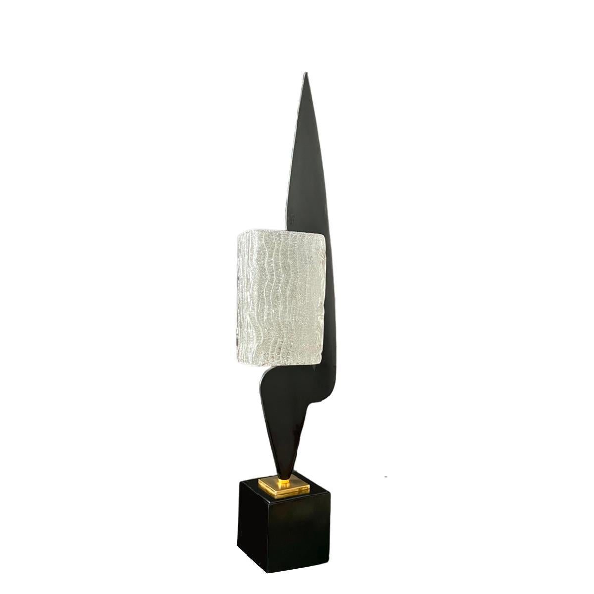Rare Arlus black lacquered wood lamp. A cubic black lacquered wooden base supports a small square brass pedestal onto which an elongated form of the same material is fixed. A rectangular thick glass lampshade engraved with wave motifs fits into the