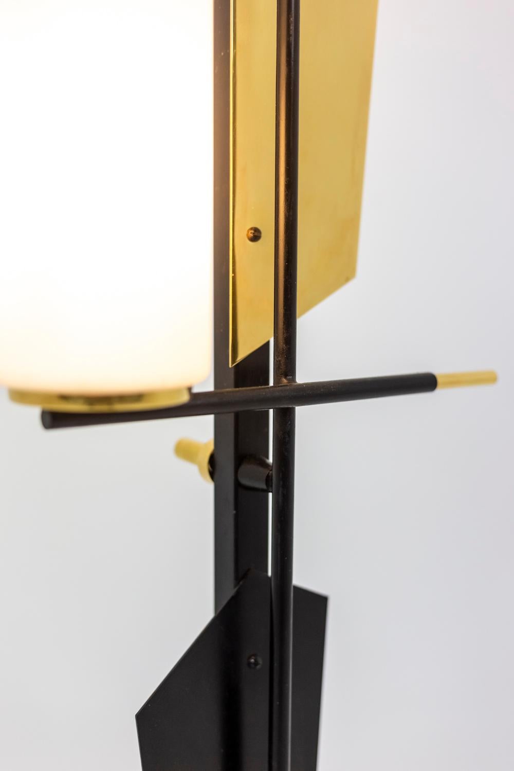 Three-light floor lamp in black lacquered metal. Decorative pieces in gilt brass and black lacquered metal on the barrel. Circular foot in lacquered metal topped with a cup in gilt brass. 

Work realized in the 1960's

Arlus was a French