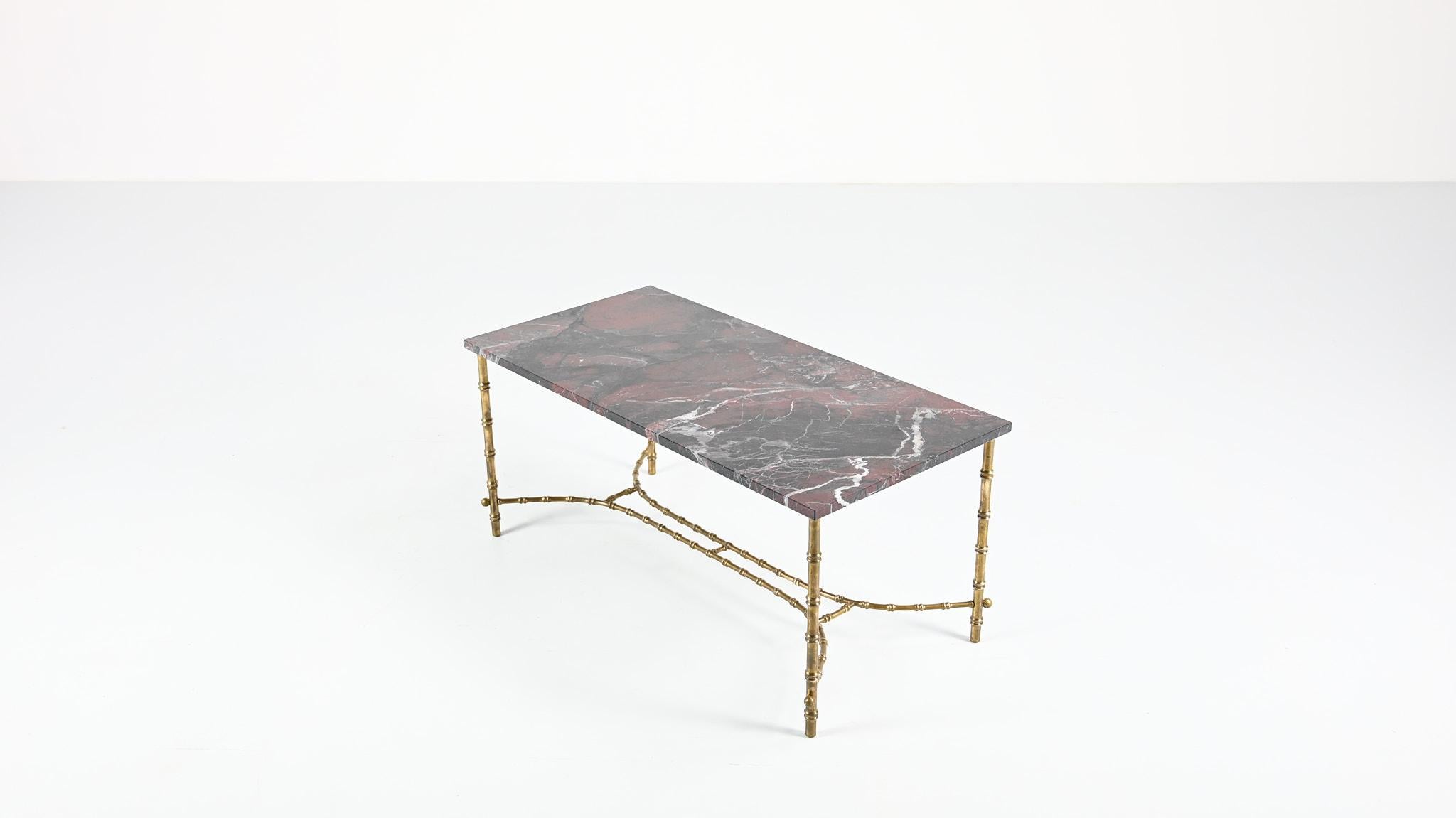 This French Neoclassical coffee table, ascribed to Maison Baguès, consist in a black and red marble top supported by a faux bambou brass structure. New marble top, excellent overall condition.