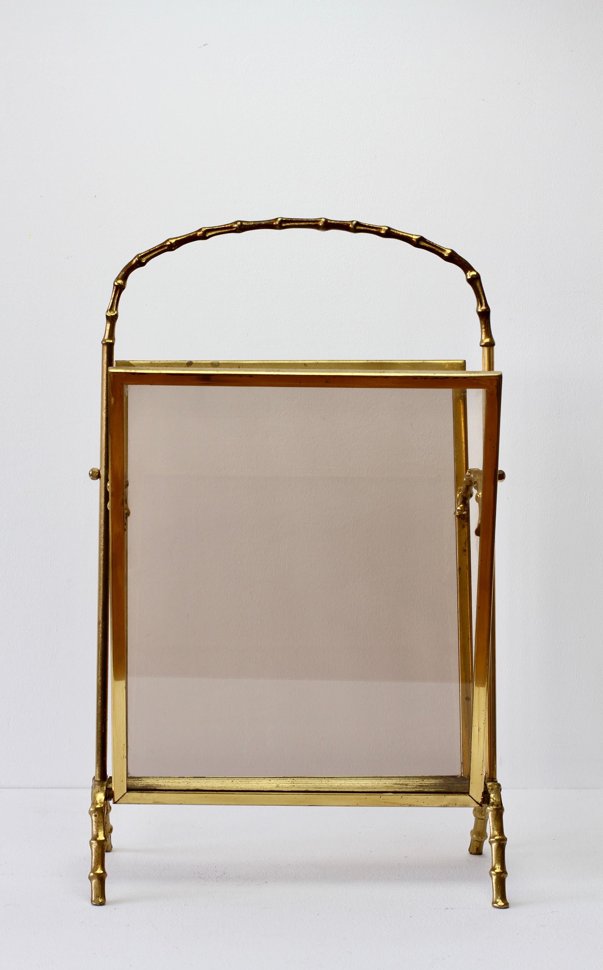 Atributo de la Maison Baguès: revistero, soporte o atril de latón fundido y cristal ahumado en tono oscuro, perfecto para el estilo Hollywood Regency, en imitación de bambú. Fabricado en Francia hacia los años 50, perfecto para cualquier