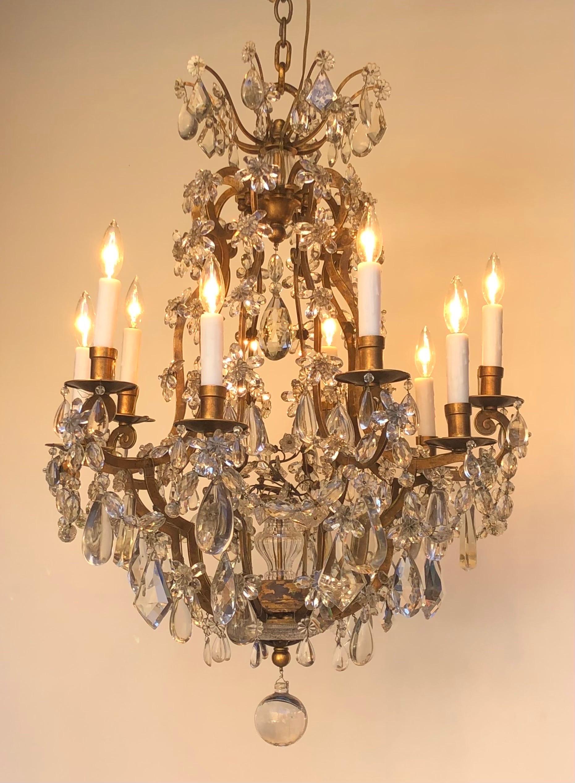 This Grand Maison Baguès gilded wrought iron crystal chandelier with ten lights was hand assembled using traditional techniques in France at the beginning of the Twentieth Century. The Fashionable Baguès chandelier has a gilt wrought iron birdcage