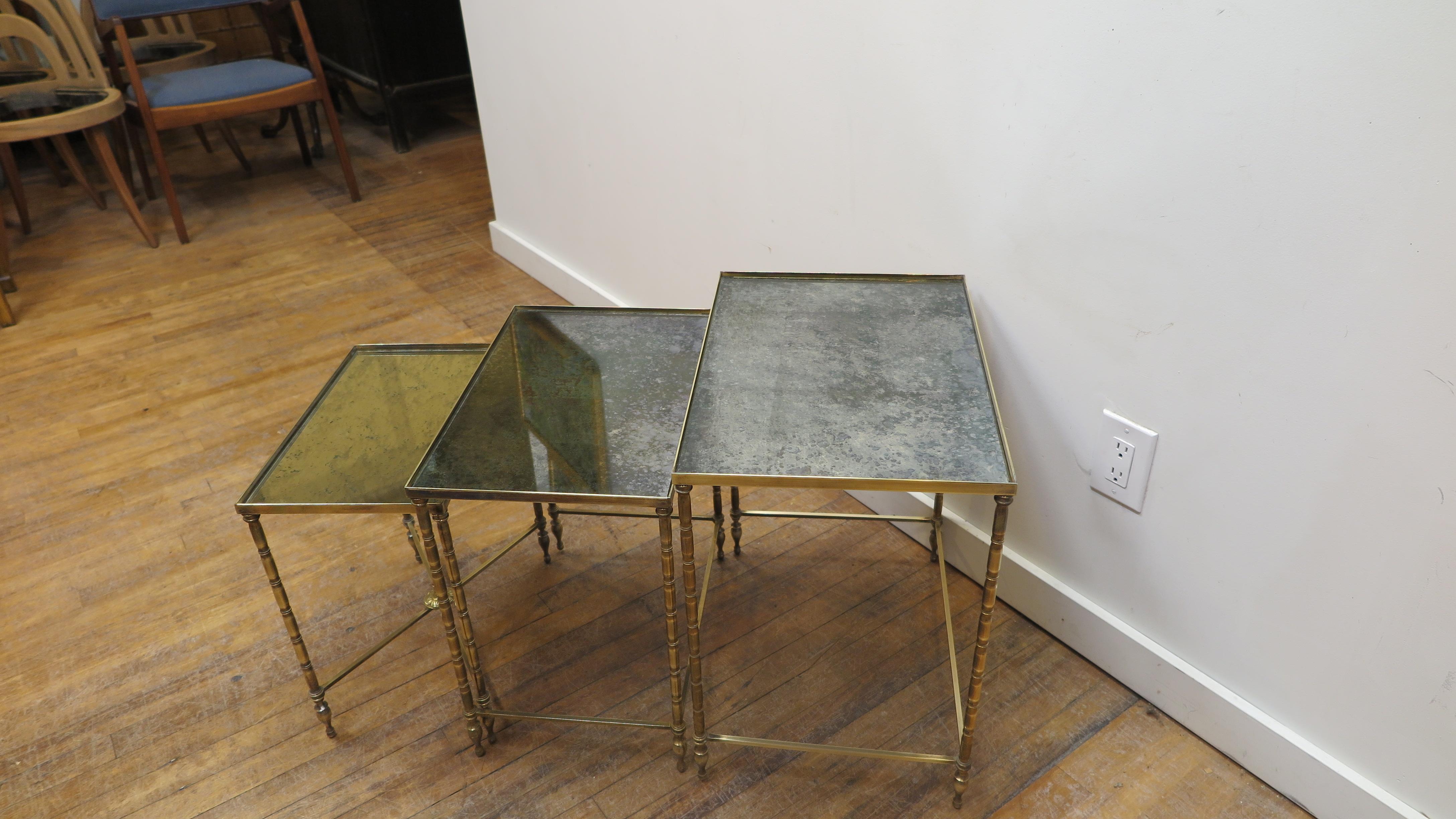 Maison Baguès set of three nesting tables. An elegant neoclassical faux bamboo style set of three nesting tables having solid bronze and brass construction with blotted mirror églomisé top. Sizes are 19.75 x 13.75 x 20.5 H, 17.75 x 11.75 x 18.5 H,