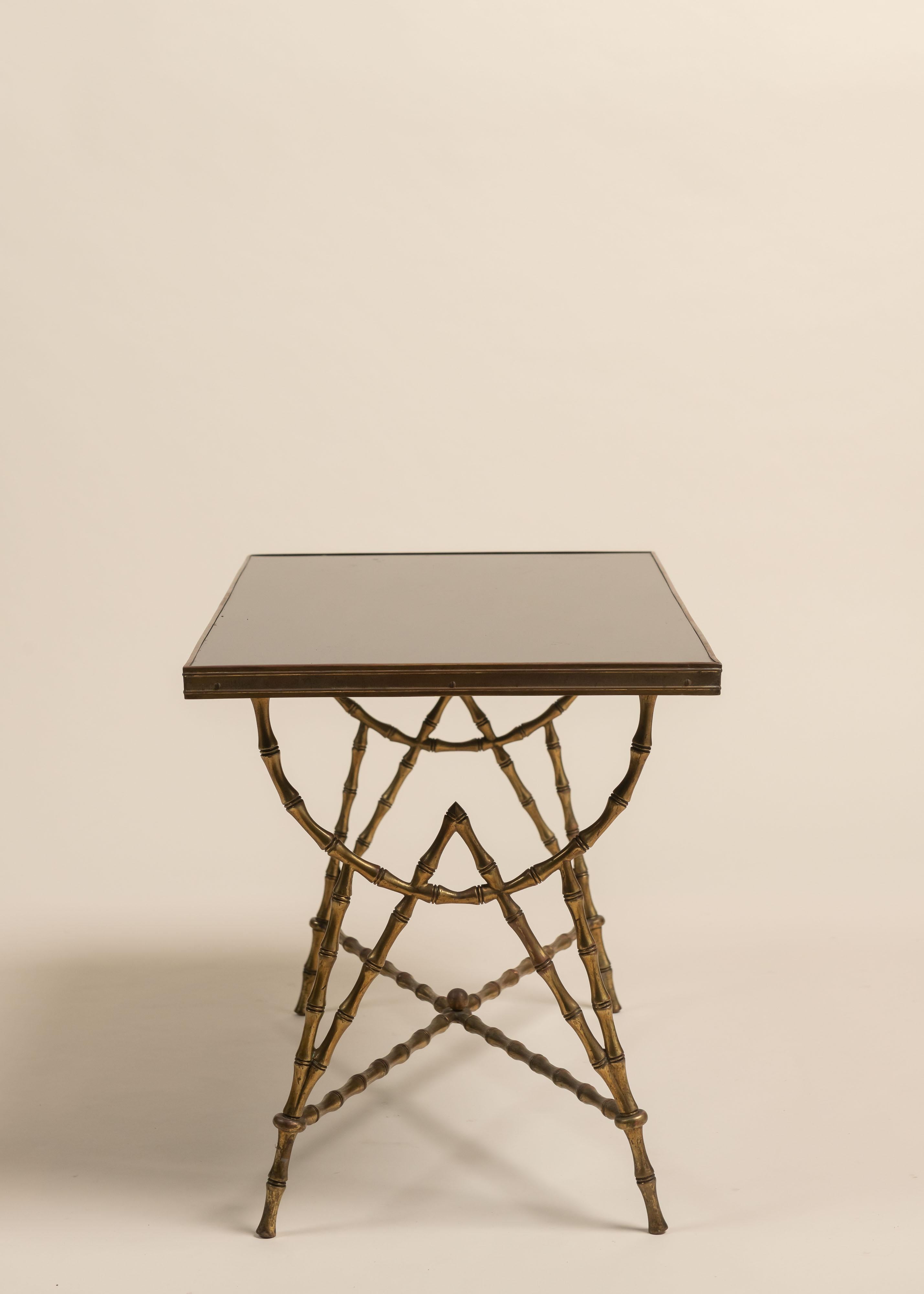 Vintage Maison Baguès cocktail table features a gilt bronze base cast in a faux bamboo motif, a signature of the Parisian design house. The legs are connected by an X-stretcher with a central finial, adding both stability and sculptural detail.