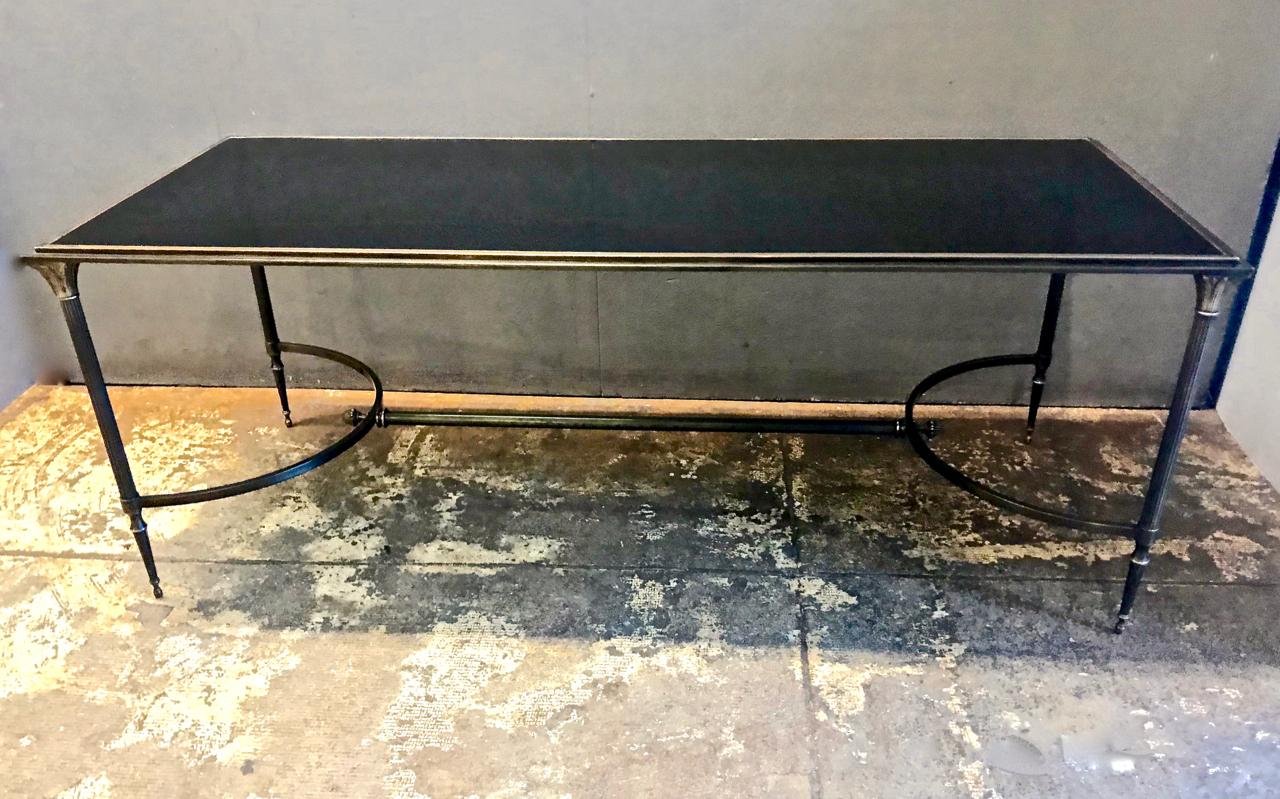 This is a Classic Maison Baguès bronze and smoked glass coffee table. The finials and leg capitals are beautifully detailed cast bronze. The leg tips are characteristic of Baguès finesse. The bronze table frame is in overall very good condition; the