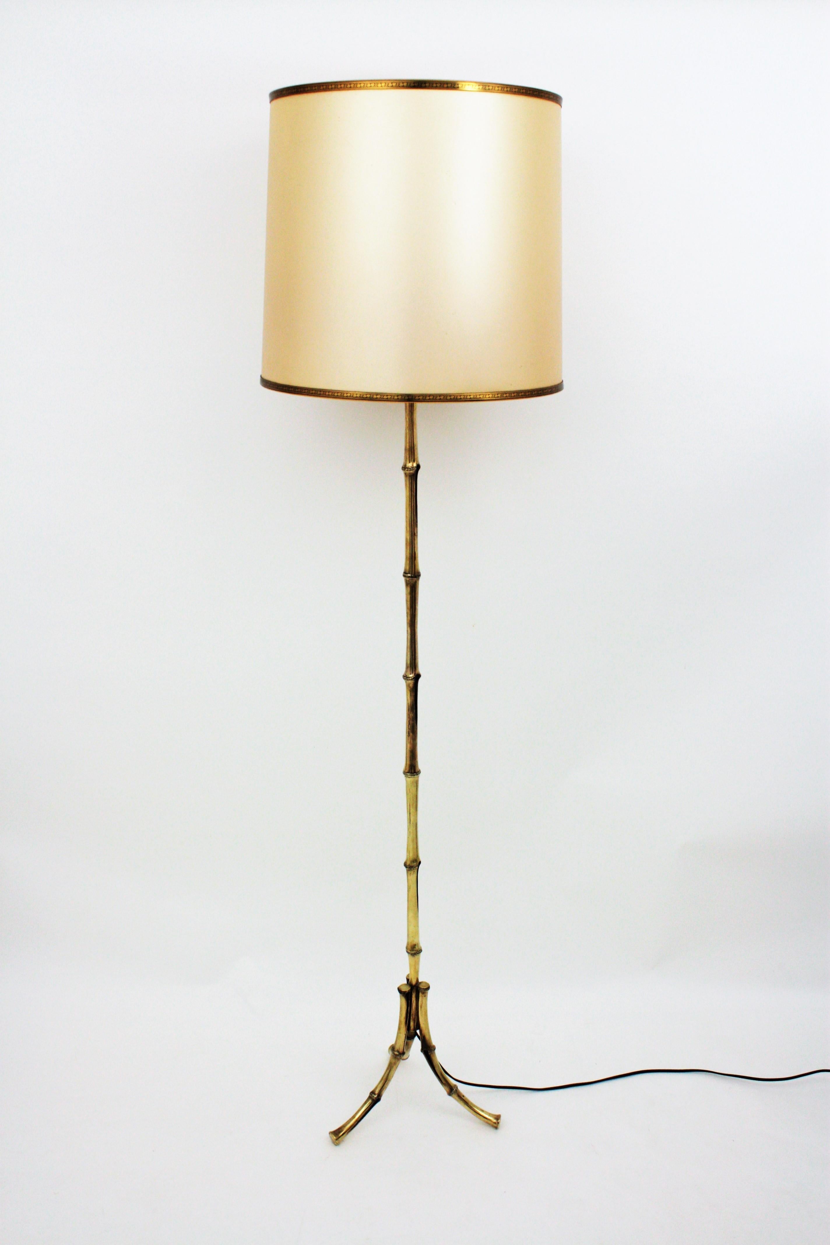 Elegant faux bamboo bronze floor lamp by Maison Baguès. France, 1950s.
Faux bamboo legs rising up to a triple canopy just under the shade.
It has three lights: a double light down socket and one upward white lacquered metal diffusor for a third