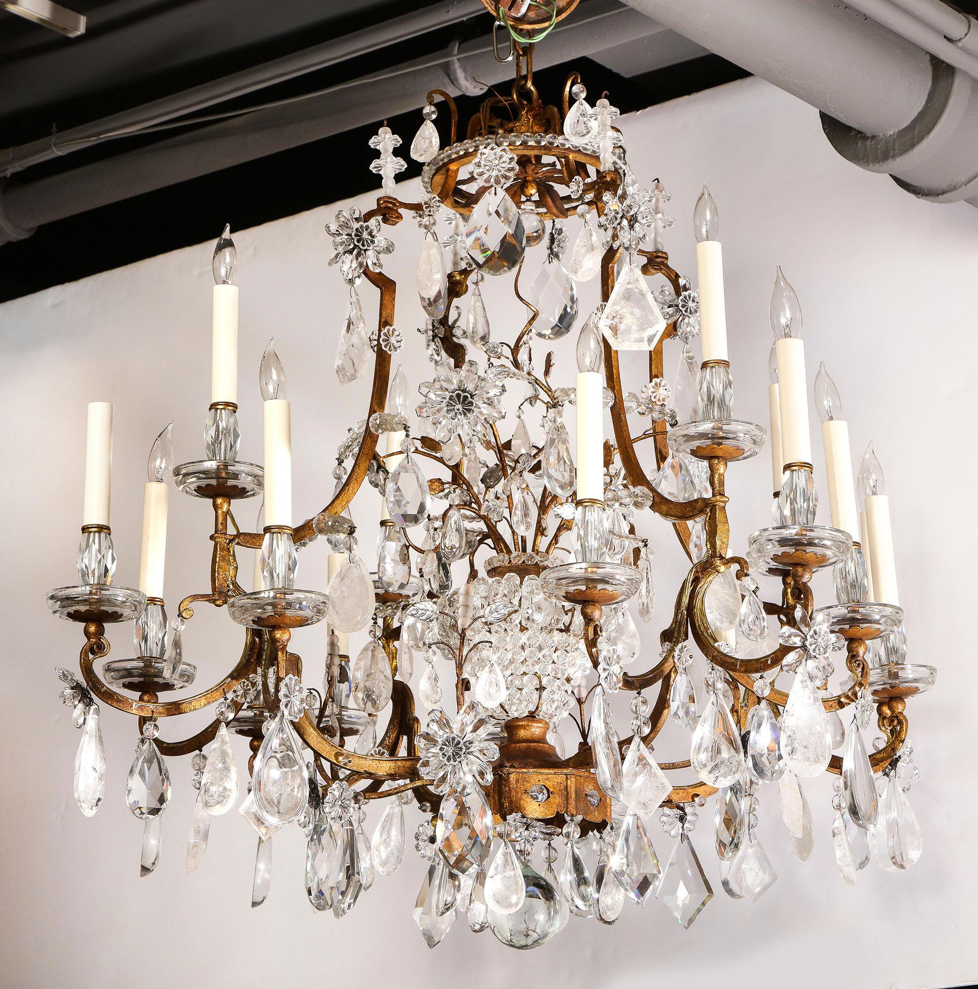 A grand rock crystal chandelier by Maison Baguès in the Louis XV style, having 12 candle lights with an interior crystal cag. The gilt frame is decorated with rock crystal and clear crystal prisms.
  