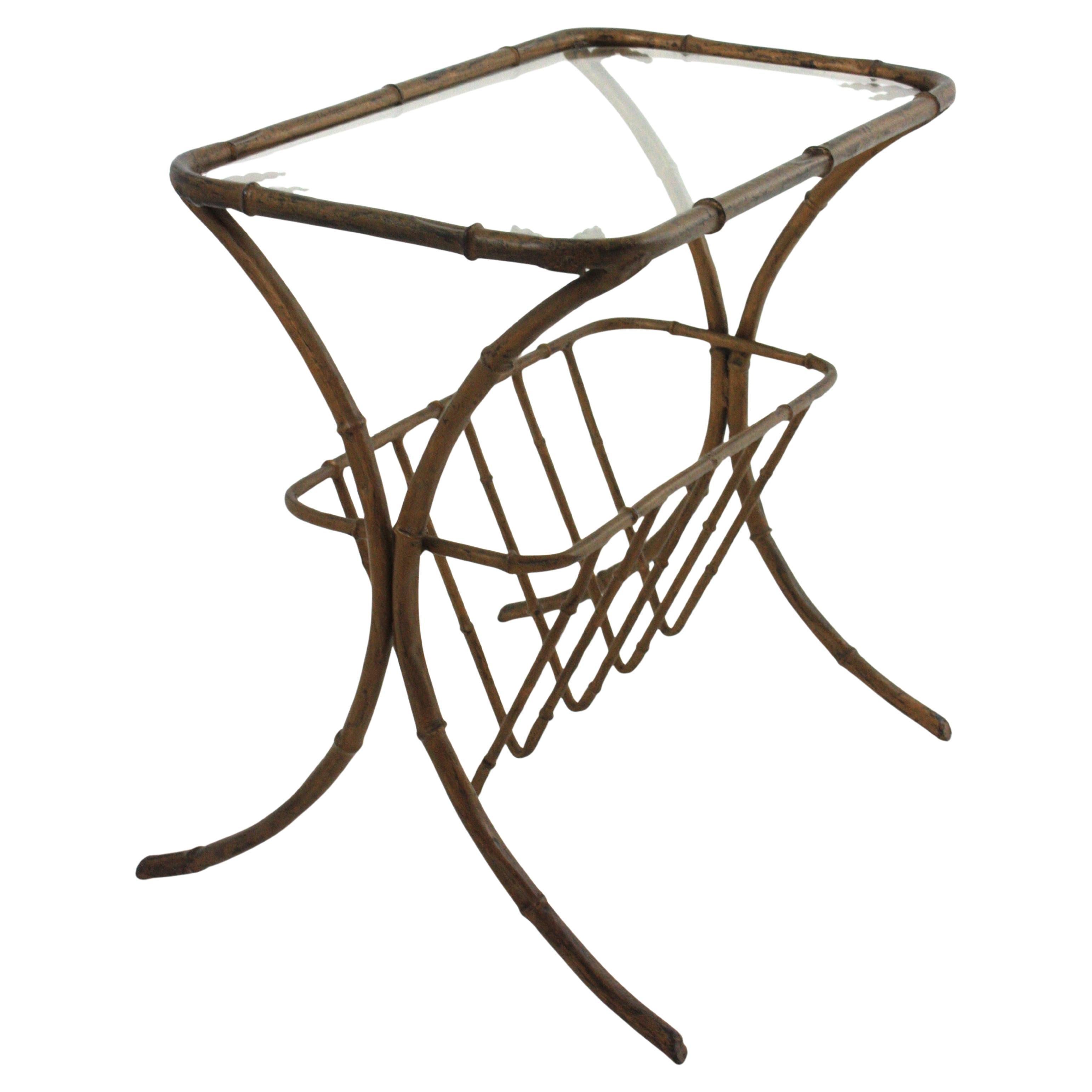 Eye-catching Hollywood Regency gilt iron faux bamboo drinks table with magazine rack and  foliage details, France, 1950s. 
In the manner of Maison Baguès.
This beautiful rectangular table has a beautiful faux bamboo design in gilt iron with glass