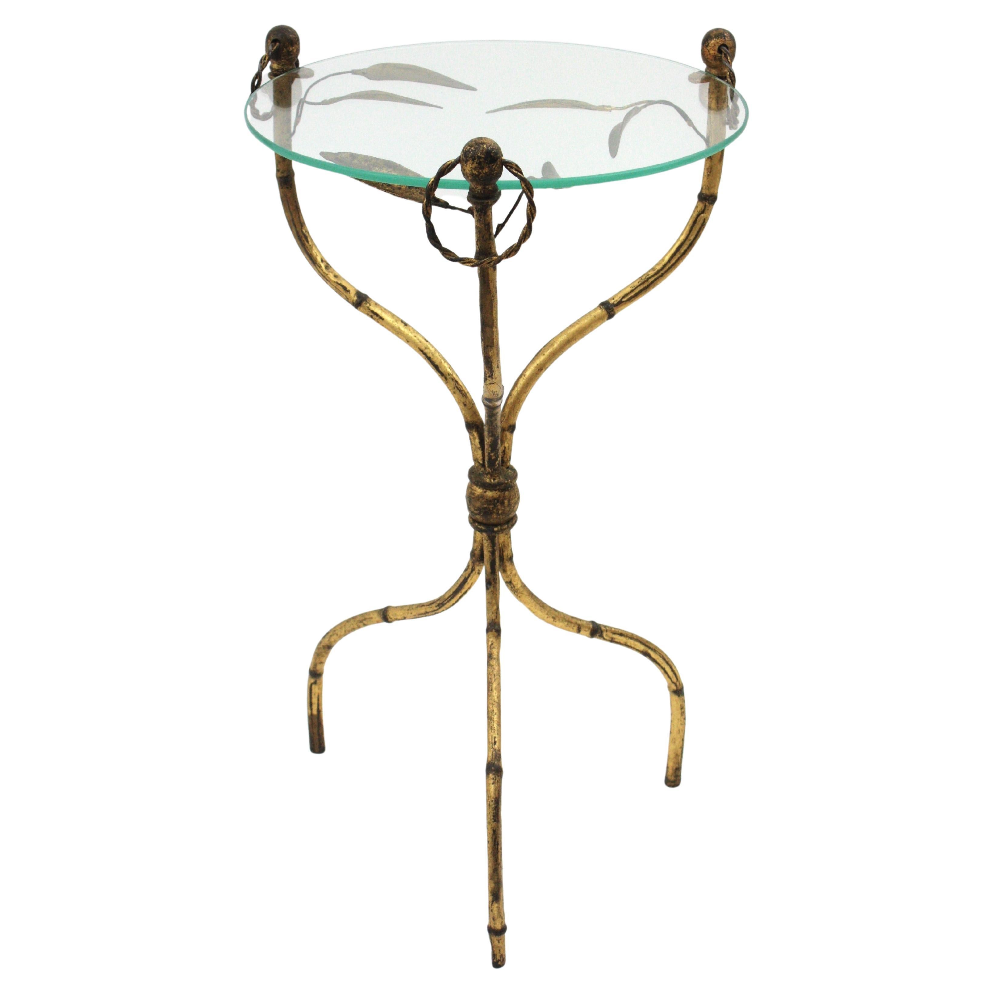 Eye-catching Hollywood Regency gilt iron faux bamboo gueridon drinks table with foliage details, France, 1950s. 
In the manner of Maison Baguès.
This beautiful round table stands up on three legs with a beautiful faux bamboo design. Leaf decorations