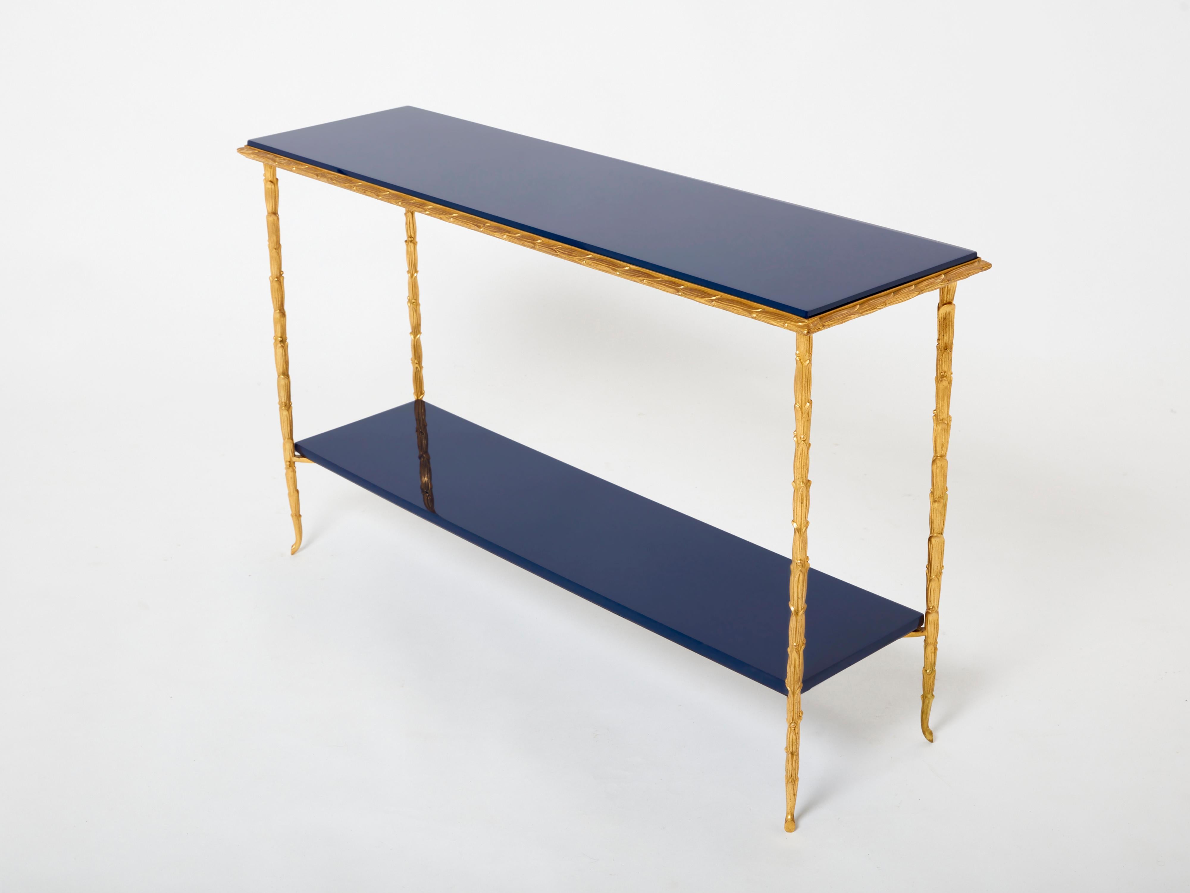 This beautiful two-tier console table by French house Maison Baguès was created in the early 1960s with solid foliage shaped bronze structure and a beautiful dark Ocean blue lacquered shelf and top. The dark blue lacquered shelves are deep and