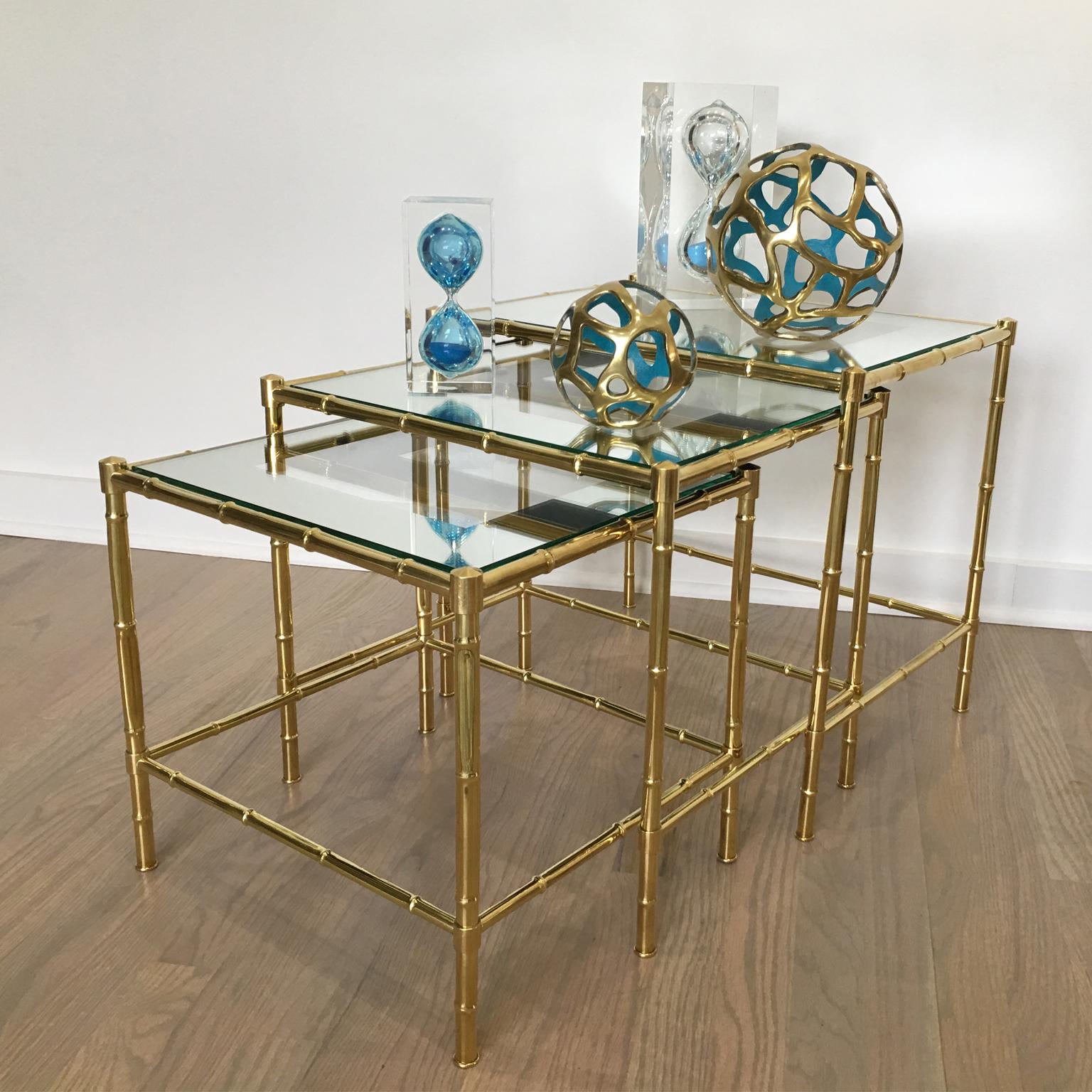 Elegant set of three nesting tables or stacking tables design attributed to Maison Bagues, France. Modernist brass frame with bamboo pattern design. Table tops are clear glass with mirror reserve. Three nice coffee or side tables that can be used