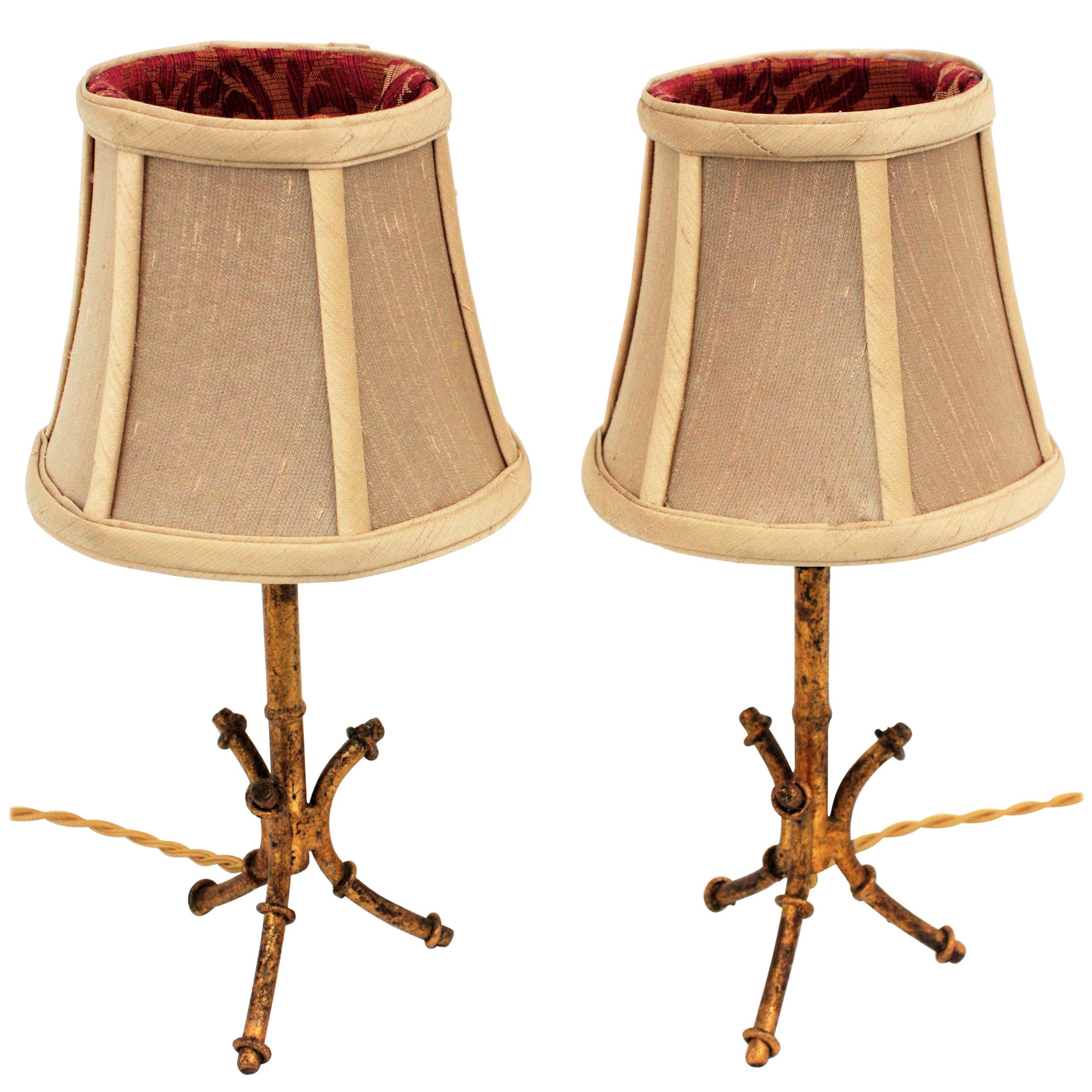 Elegant Hollywood Regency bamboo inspired gilt iron tripod table lamps in the style of Maison Baguès. France, 1950s
These lamps have new upholstered shades: a raw silk fabric in sand color at the external part and a burgundy and gold jacquard