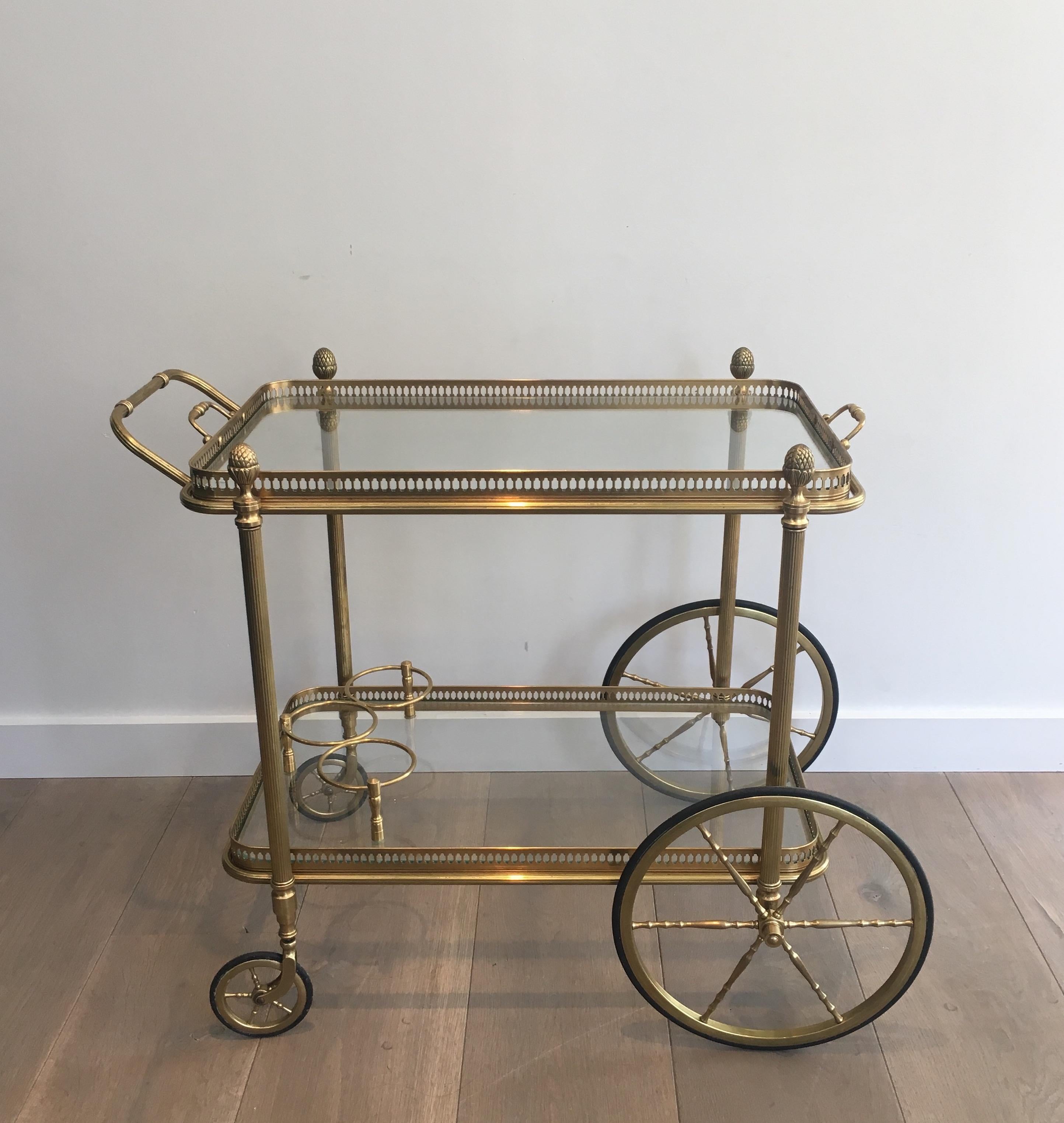 This neoclassical style bar cart is made of brass with removable glass trays. This is a work by famous designer Maison Bagués, circa 1940.
