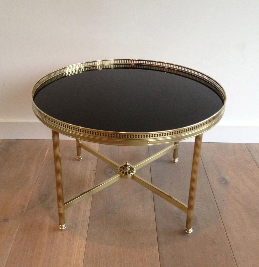 This neoclassical style round coffee table is made of brass with a black lacquered glass top. This is a very nice and fine work by famous French designer Maison Baguès, circa 1940.