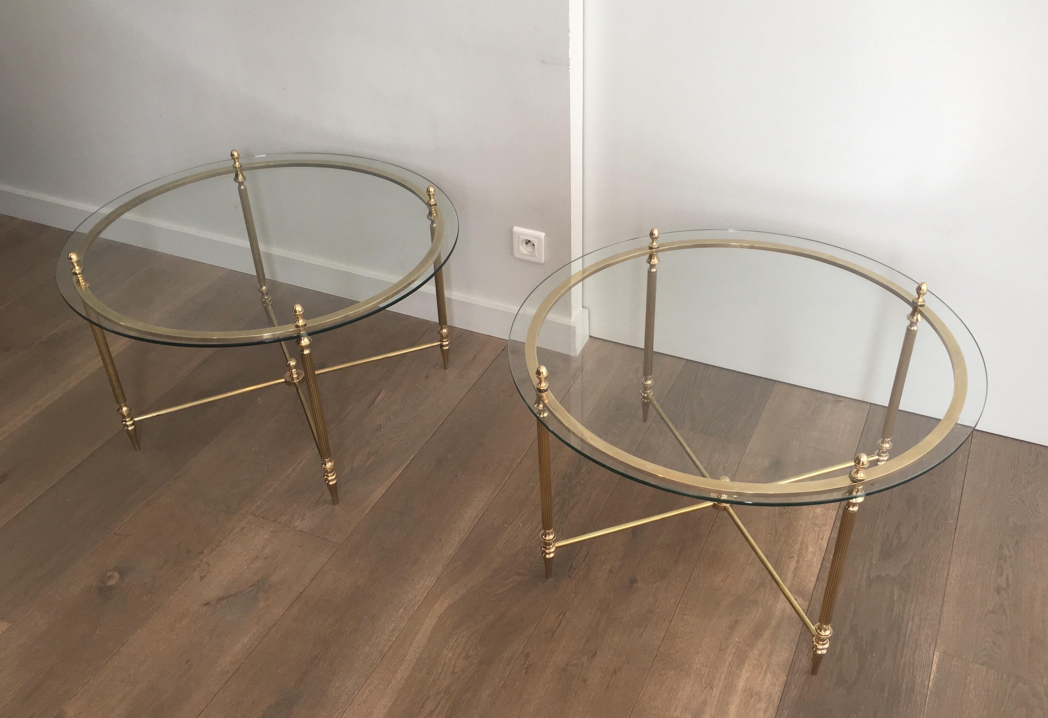 This rare pair of neoclassical round side tables are made of brass with a clear glass top. These are very nice side tables by famous french designer Maison Bagués, circa 1940.