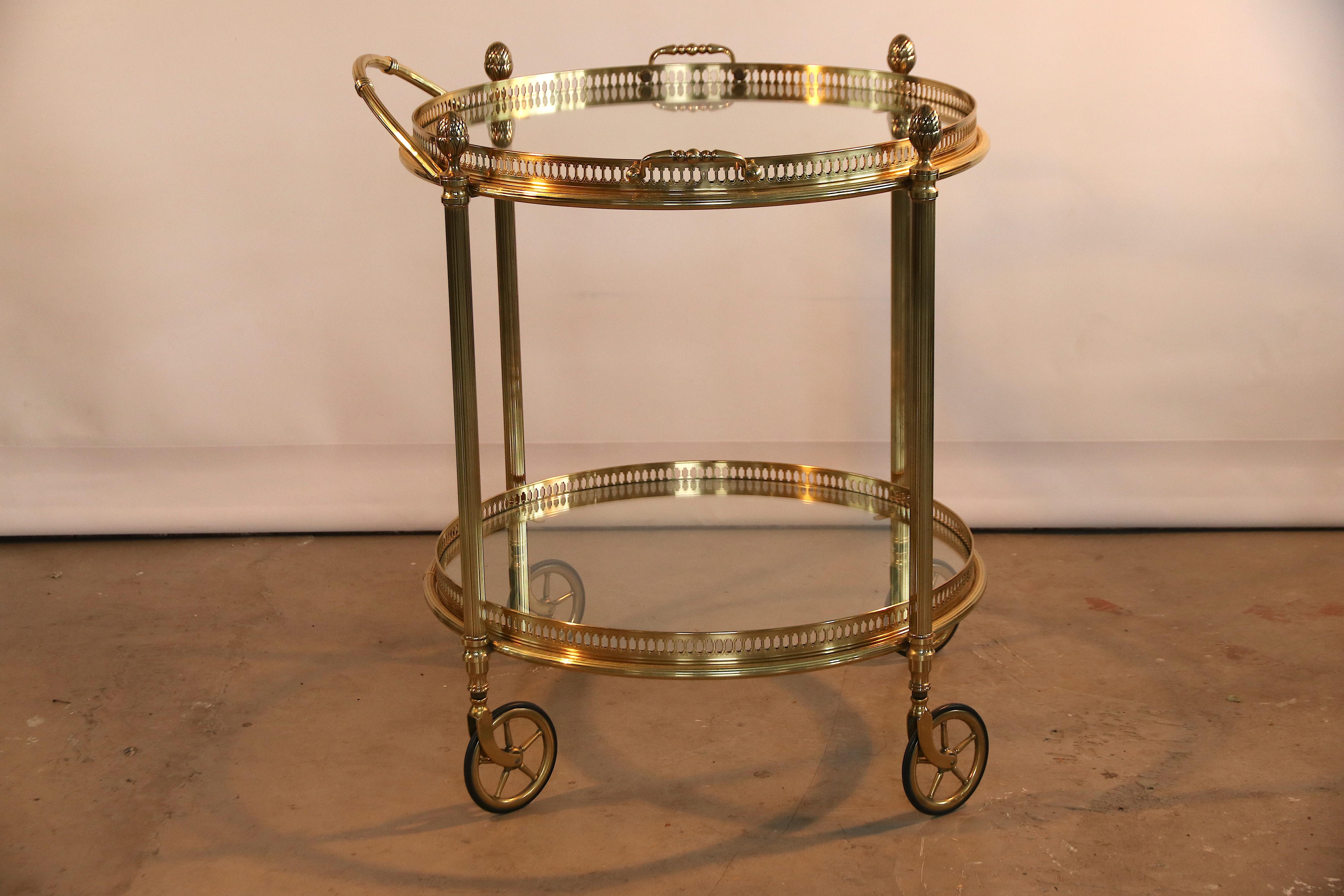 Very stylish old late 1940s 2-tier round full brass serving trolley on 4 casters with two glass tops for bottles and glasses. The upper top with handles can be used as standalone tray for serving drinks and food (breakfast). This piece is in a