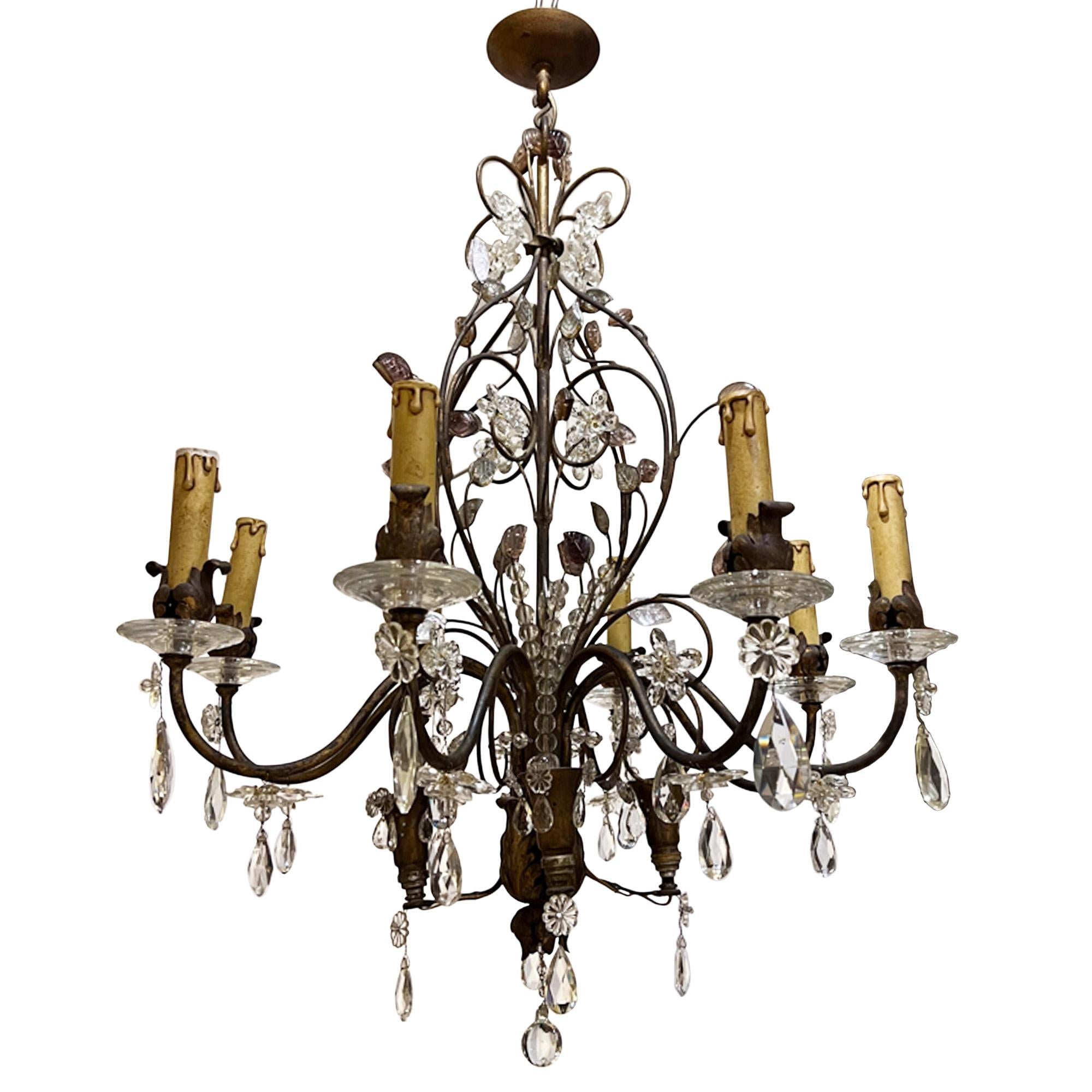 This charming chandelier was made in France in the 1950s in the style of Maison Baguès. 

The elegant gilt metal frame is trimmed with glass and crystal flowers and leaves. There are 8 arms and 4 further bulb fittings clustered at the bottom. 

Some