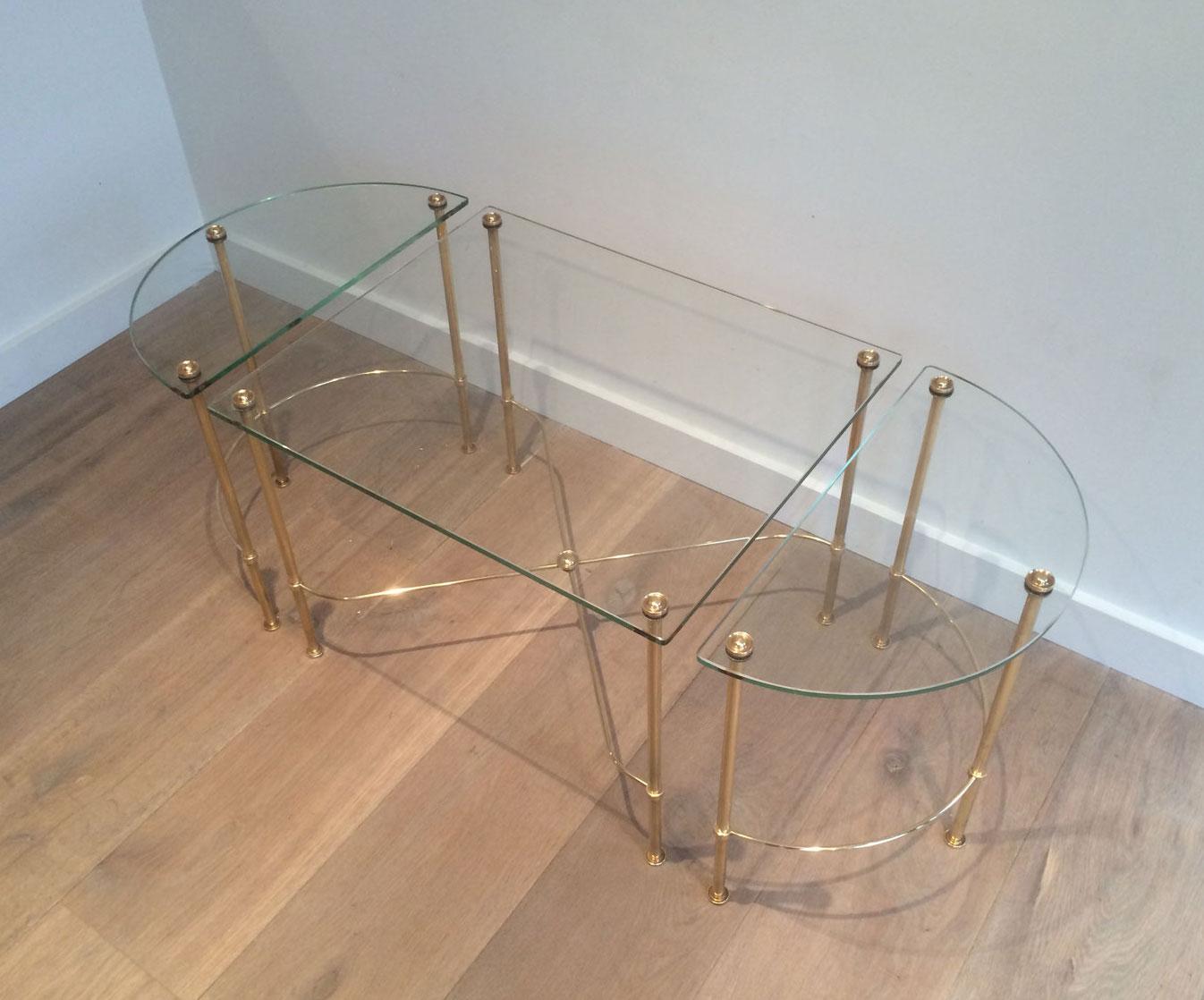 This beautiful neoclassical style tripartite coffee table is made of brass with glass shelves rounded on the side tables. This is a very nice work by famous French designer Maison Bagués, circa 1970.