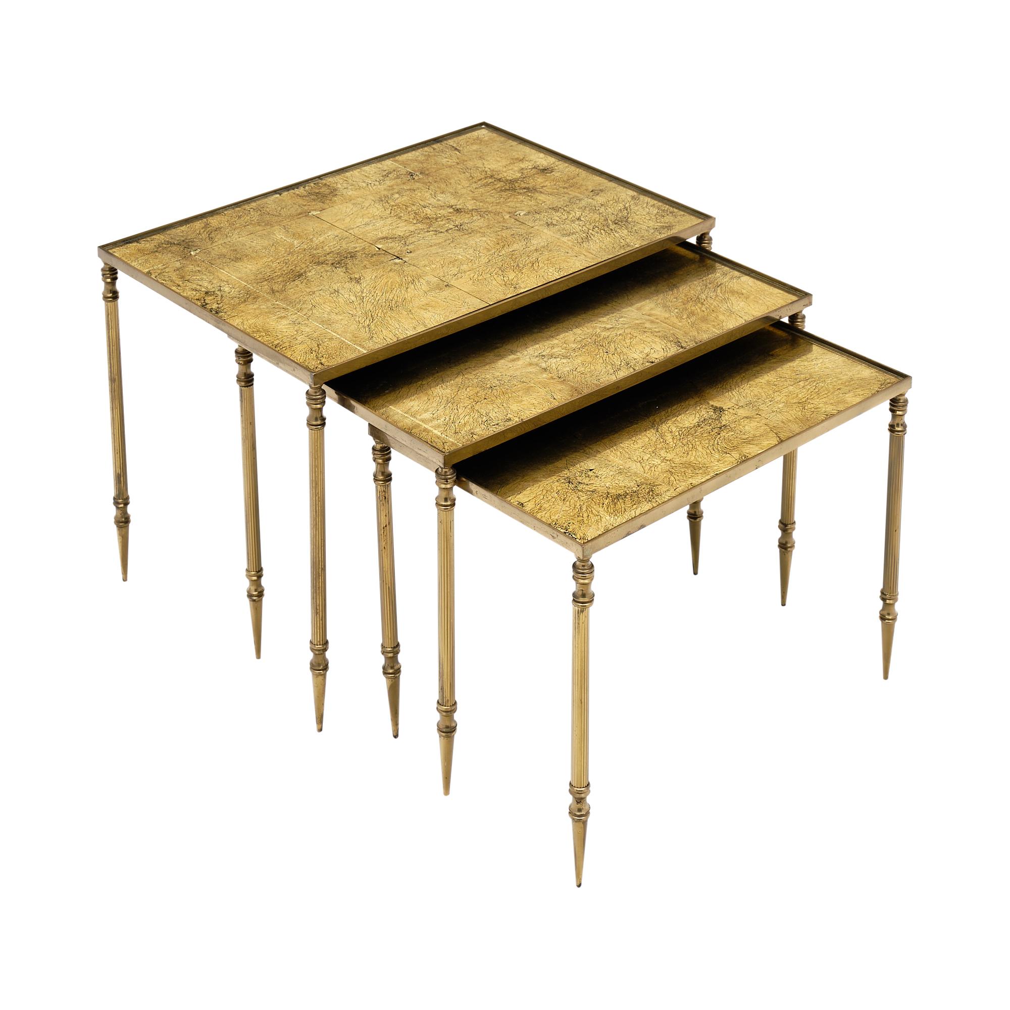 Set of three nesting tables from France made of ridged gilt brass and 24 carat gold leafed glass by Maison Baguès. 

Large table
H-15.625”
L- 21.75”
D- 15.75”.

Medium table
H- 14.5”
L- 19.625”
D- 13.875”

Small table
H- 13.375”
L-