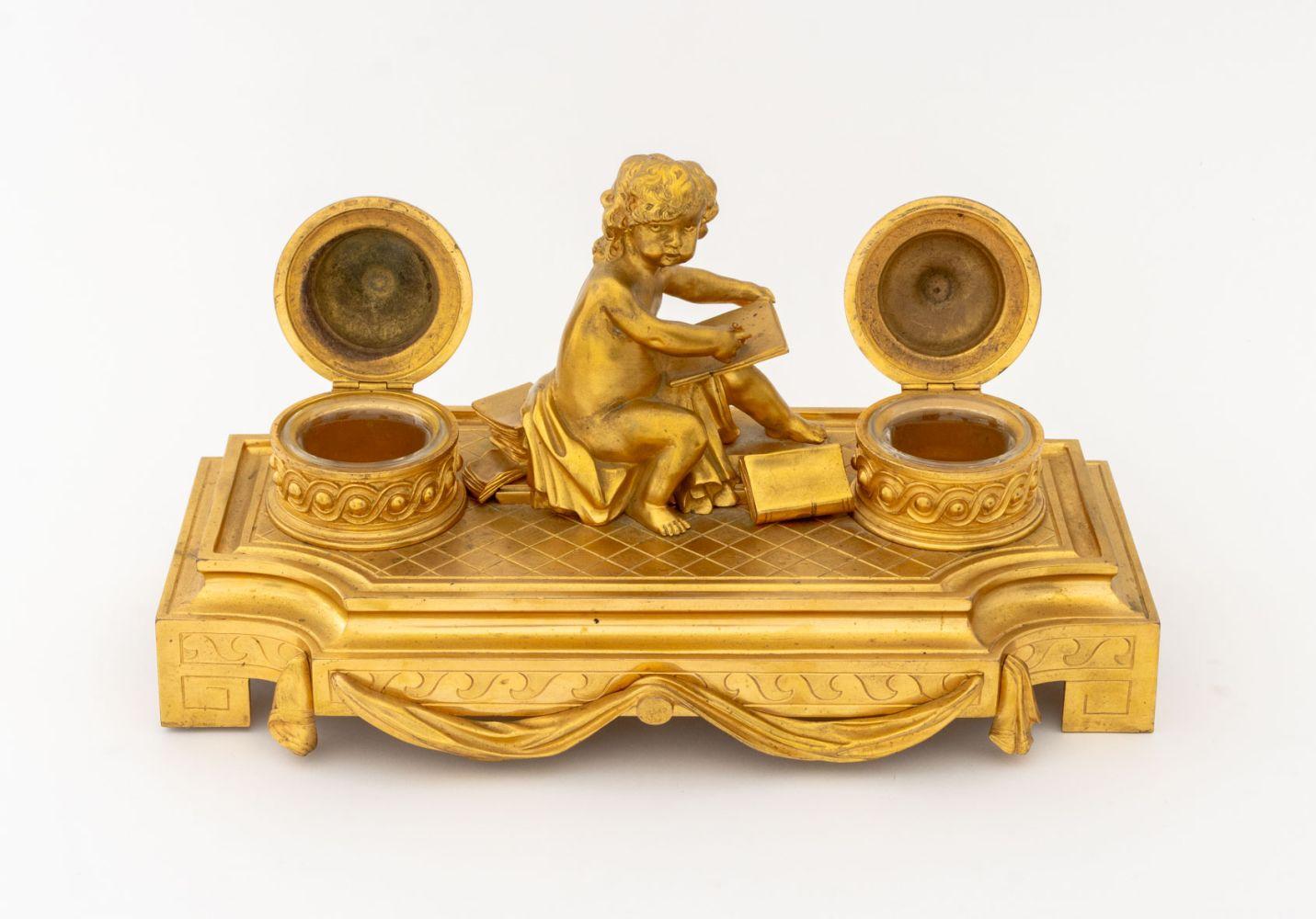 Maison Boin-Taburet - Calamaio francese in bronzo ormolato, fine XIX secolo, con cherubino che scrive su una tavoletta circondato da libri affiancato da due calamai coperti con inserti in vetro trasparente, con la scritta 