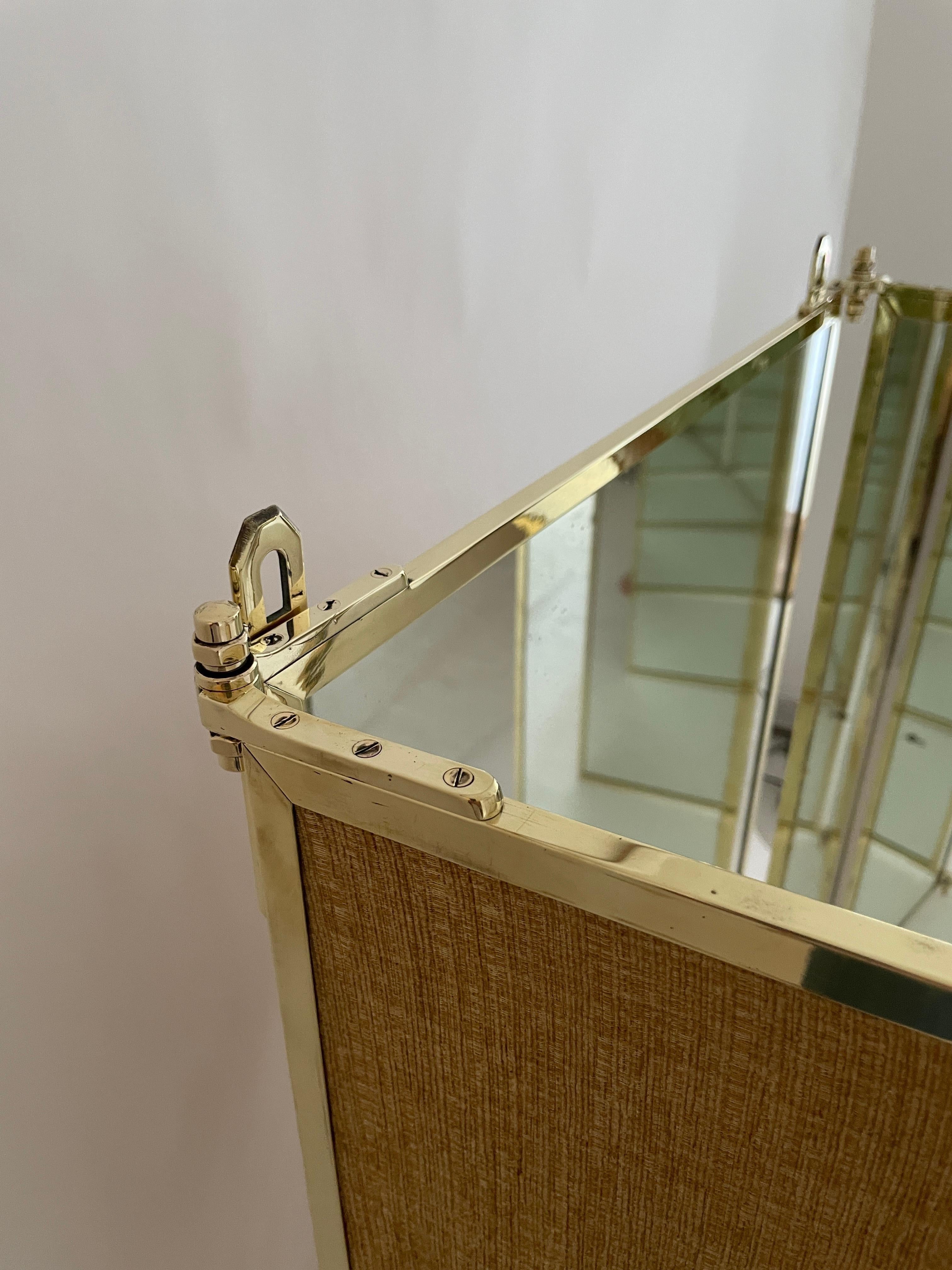 This is an very early production Maison Brot mirror.

Brot Miroirs (Established 1826). A dressing mirror, circa 1940. Three folding panels in a brass frame, with two wall fixtures to the top of the central mirror. Each panel: 51 1/4 in. (130 cm.)