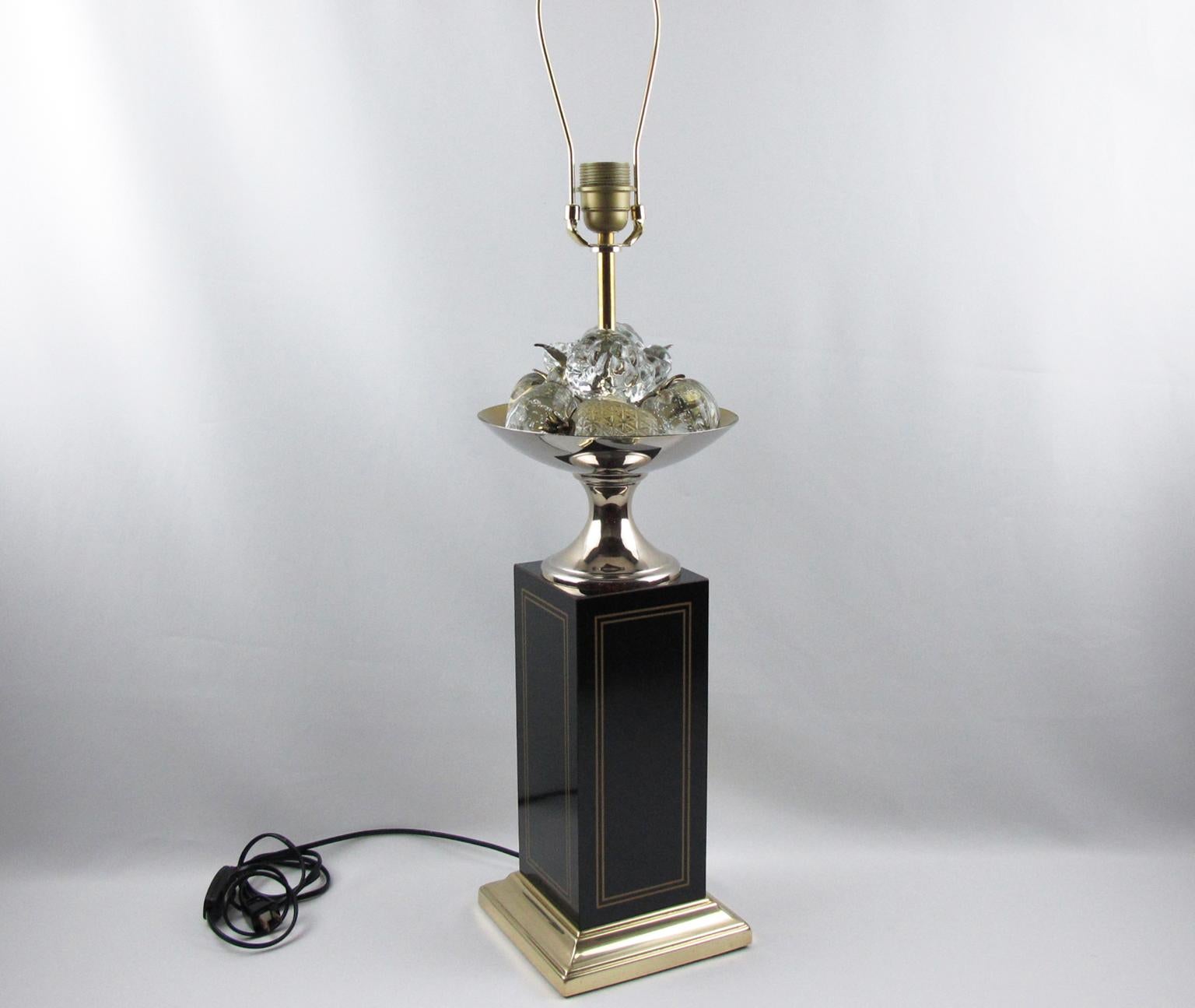 Maison Charles, Paris, designed this stunning decorative tall table lamp. A large black enameled square column with inlaid brass details elevates the entire lighting piece. The lamp is topped with a brass bowl holding crystal fruits with brass stems