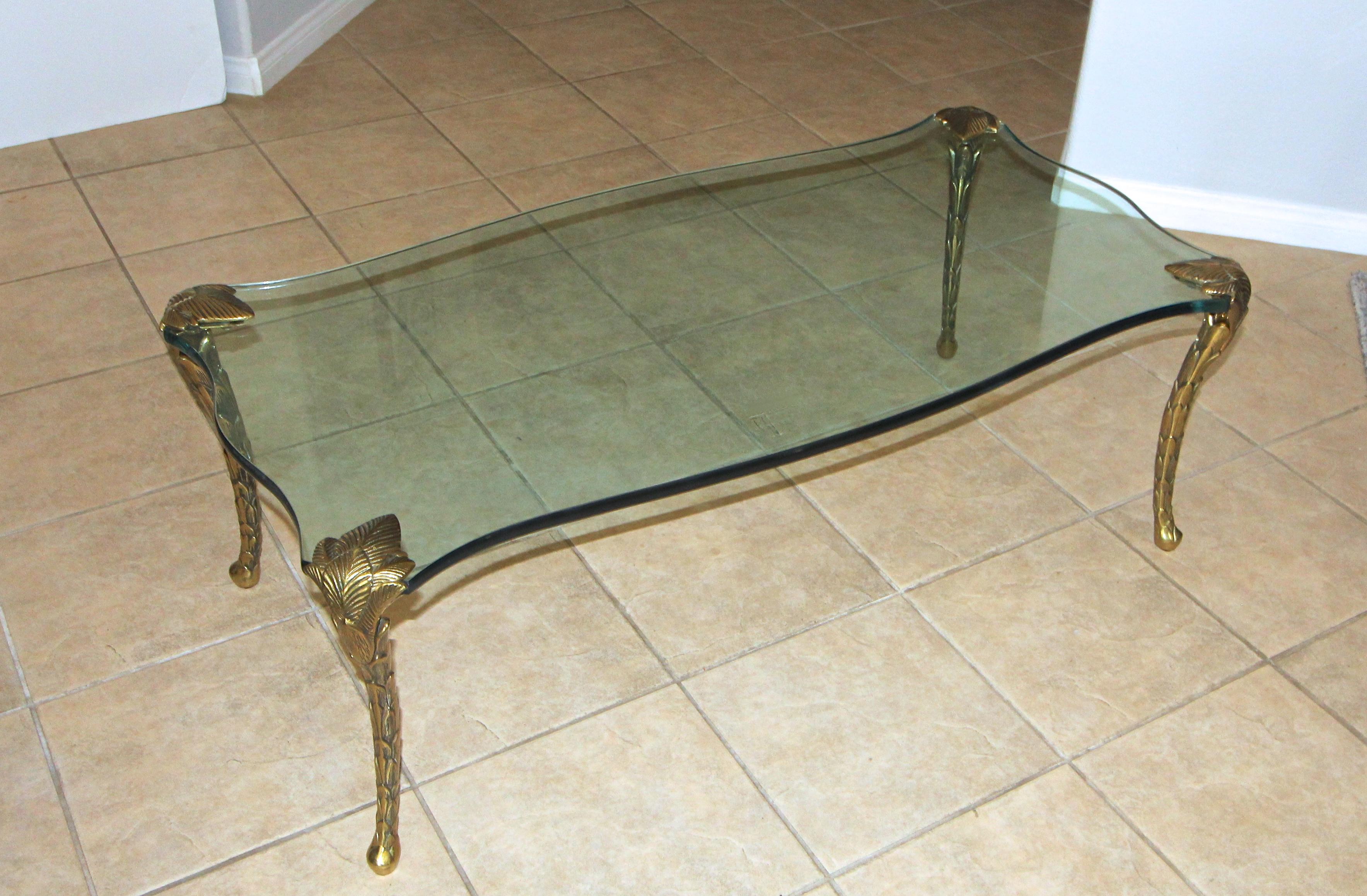 Thick serpentine shaped glass top, resting on four foliate cabriole brass or bronze legs coffee or cocktail table, attributed to Maision Charles.