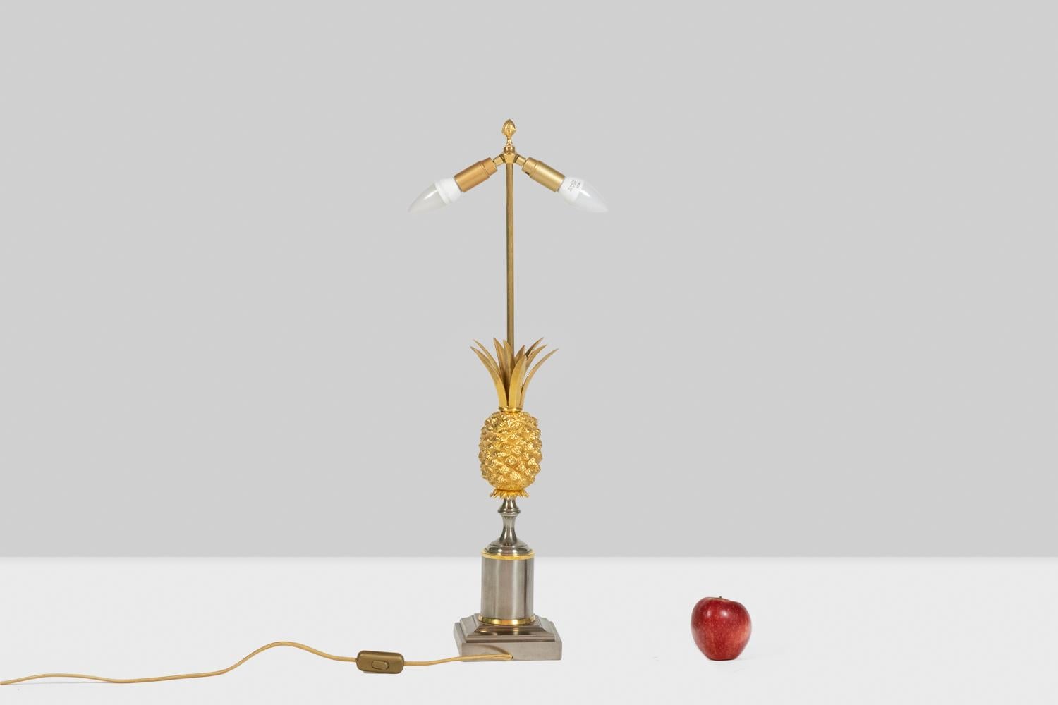 Lampe en bronze doré représentant un ananas stylisé. Base argentée polie. Abat-jour original en tôle argentée, se terminant en haut par une houppe stylisée.

Dimensions : H 74 x L 14 x P 14 cm : H 74 x L 14 x P 14 cm

Travail français réalisé dans