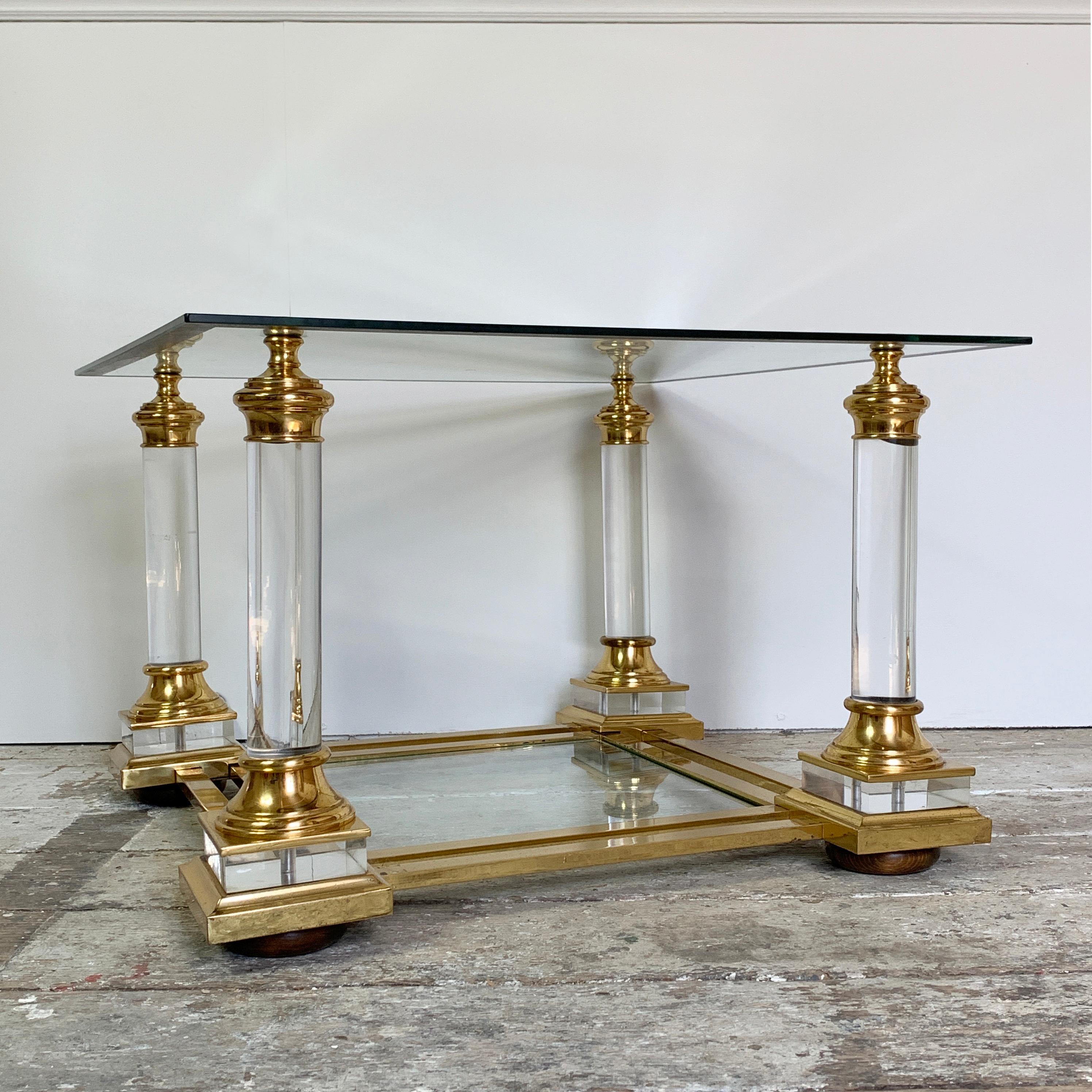Midcentury Lucite and glass coffee table
Maison Charles,
circa 1950s
Lucite columns on each corner supporting a mirror banded edge, clear glass top
underneath a double banded brass frame supports a further clear glass shelf
some tarnishing to