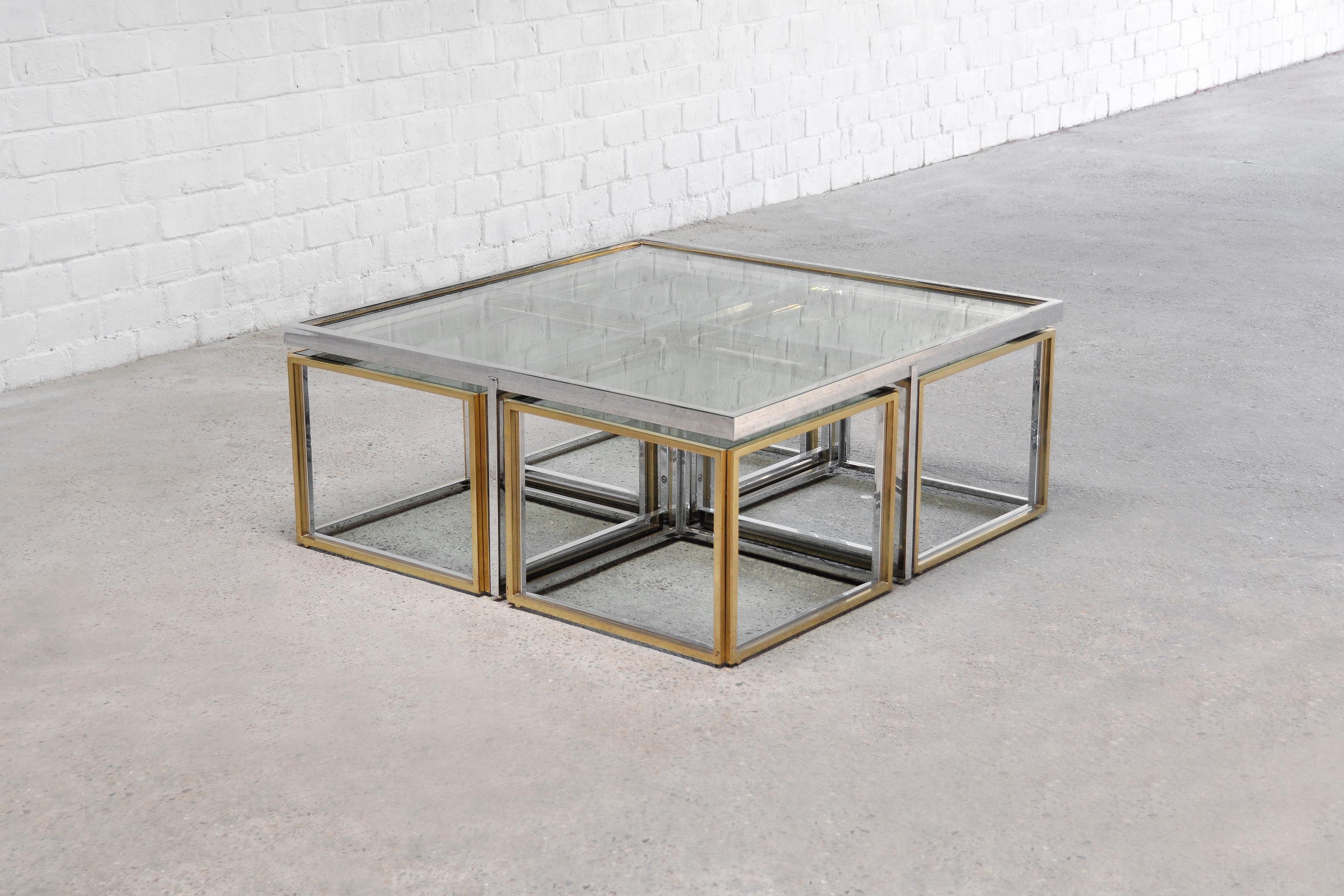 A beautiful large coffee table made out of glass, brass and metal with four side/nesting tables. Produced by Maison Charles in France, 1970's. The four smaller side tables can be pushed under the larger center table and are completely modular,