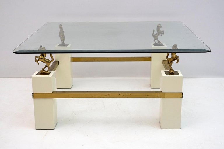 This French coffee table was produced in the 1970s by Maison Charles. The table has a brass structure, glass top with grinding. The four horses in polished brass rest on an ivory lacquered wooden base.
