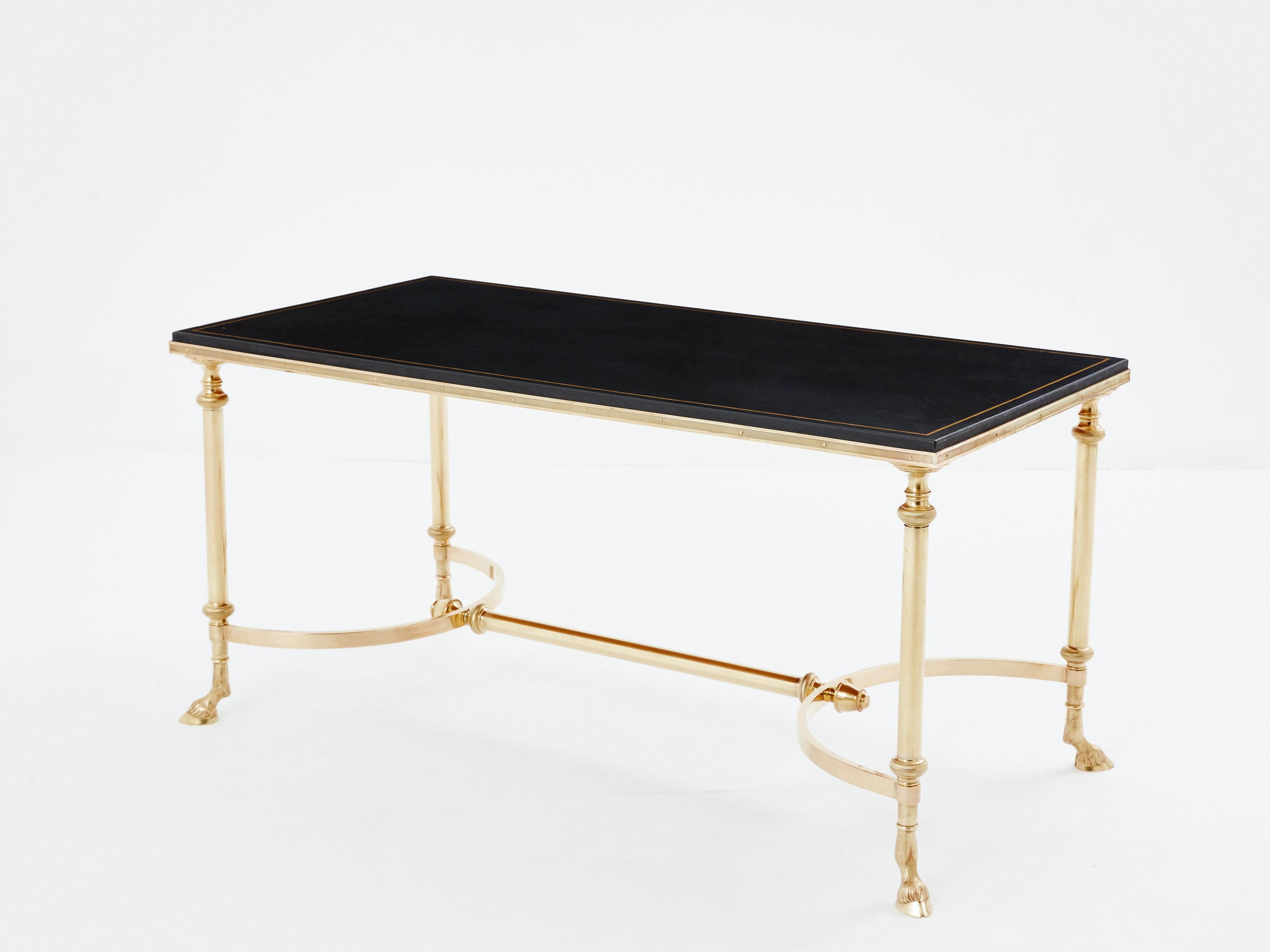 This beautiful coffee table by Maison Charles was produced with solid brass and black leather top in the early 1970s. The table is full of Neoclassical character, with its structure, goat hooves, and leather top. It has been fully restored, the