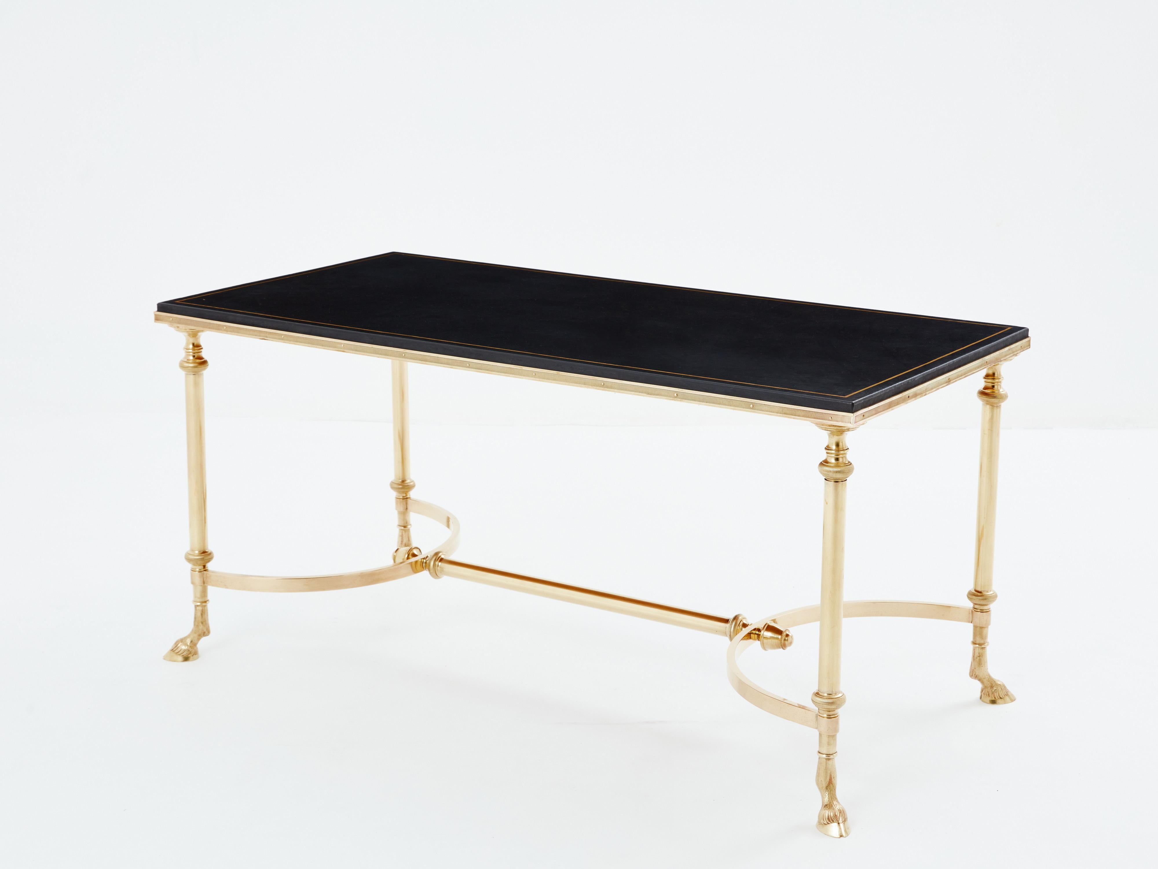 Cette magnifique table basse de Maison Charles a été produite avec du laiton massif et un plateau en cuir noir au début des années 1970. La table présente un caractère néoclassique, avec sa structure, ses sabots de chèvre et son plateau en cuir. Il