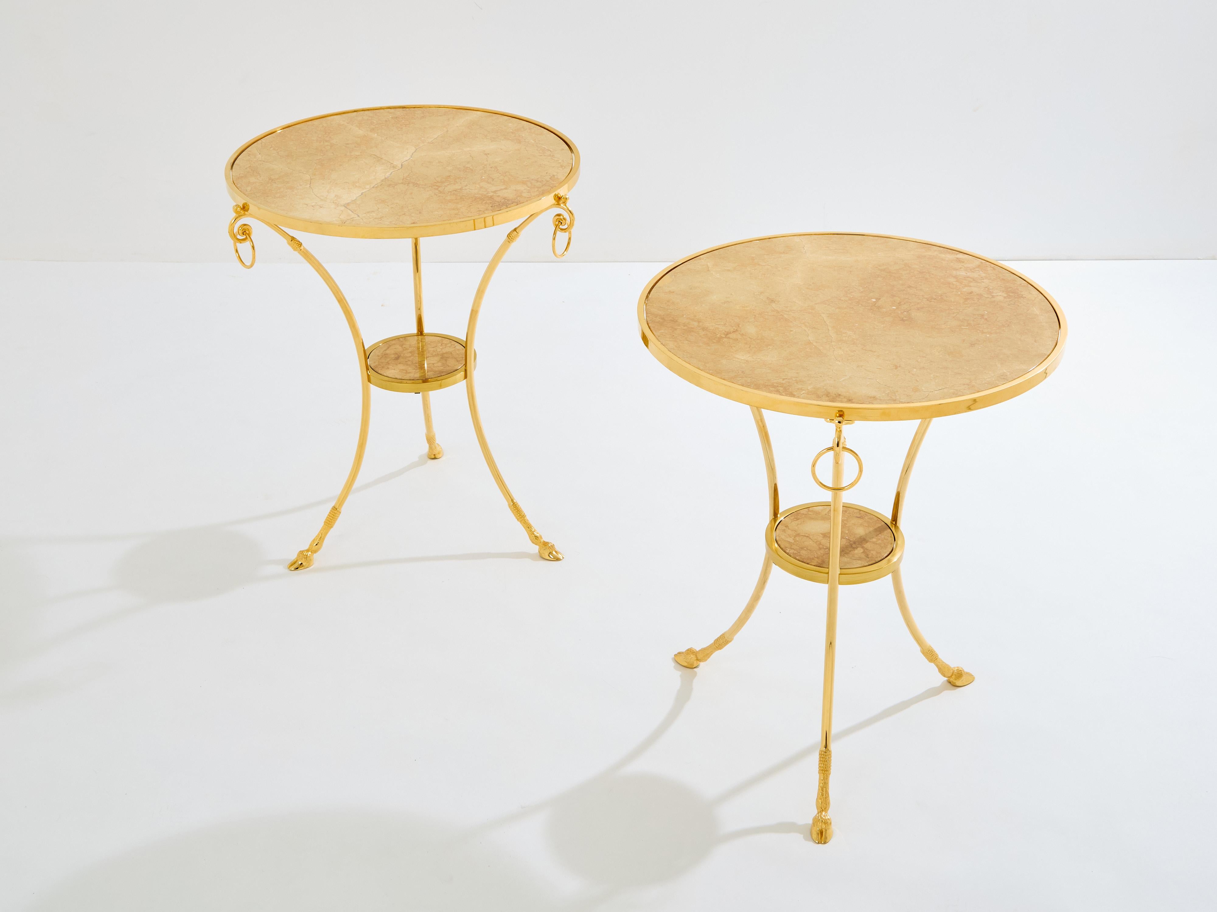 Questa coppia di tavolini gueridon degli anni '60 è un bellissimo esempio di design neoclassico francese della Maison Charles. La struttura in ottone massiccio con gambe a sciabola drammaticamente ricurve, i piani in marmo a due livelli e gli anelli