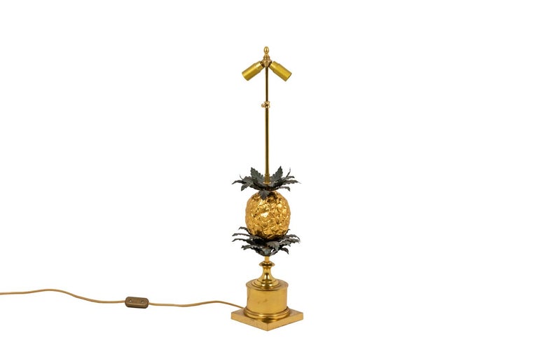 Large lamp representing a stylized pineapple in gold-plated bronze and crowned by leaves in embossed and gilt brass. Under the pineapple, the tree is symbolized by a more important triple crown of leaves in gilt brass. The whole stands on a gilt