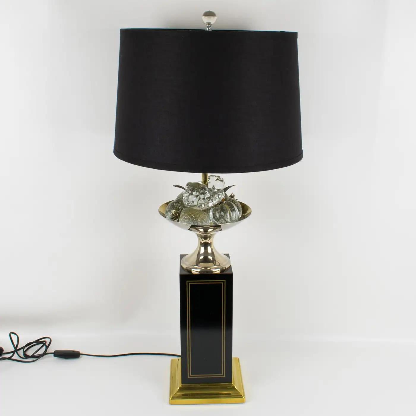Maison Charles, Paris, designed this stunning decorative tall table lamp. A large black enameled square column with inlaid brass details elevates the entire lighting piece. The lamp is topped with a brass bowl holding crystal fruits with brass stems