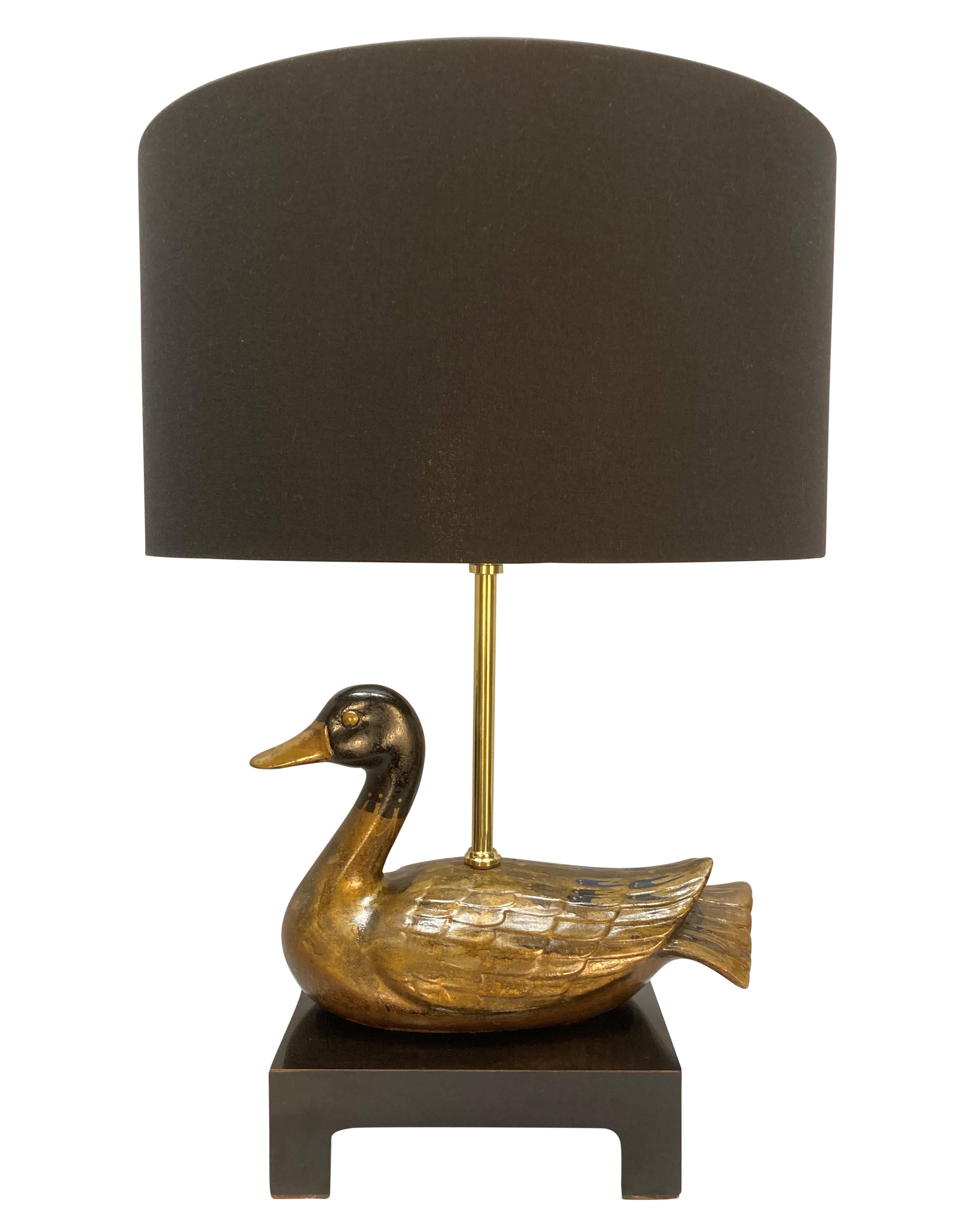 A French table lamp depicting a hand painted duck, by Maison Charles. In black resin and brass, with a black drum shade lined with tigers.