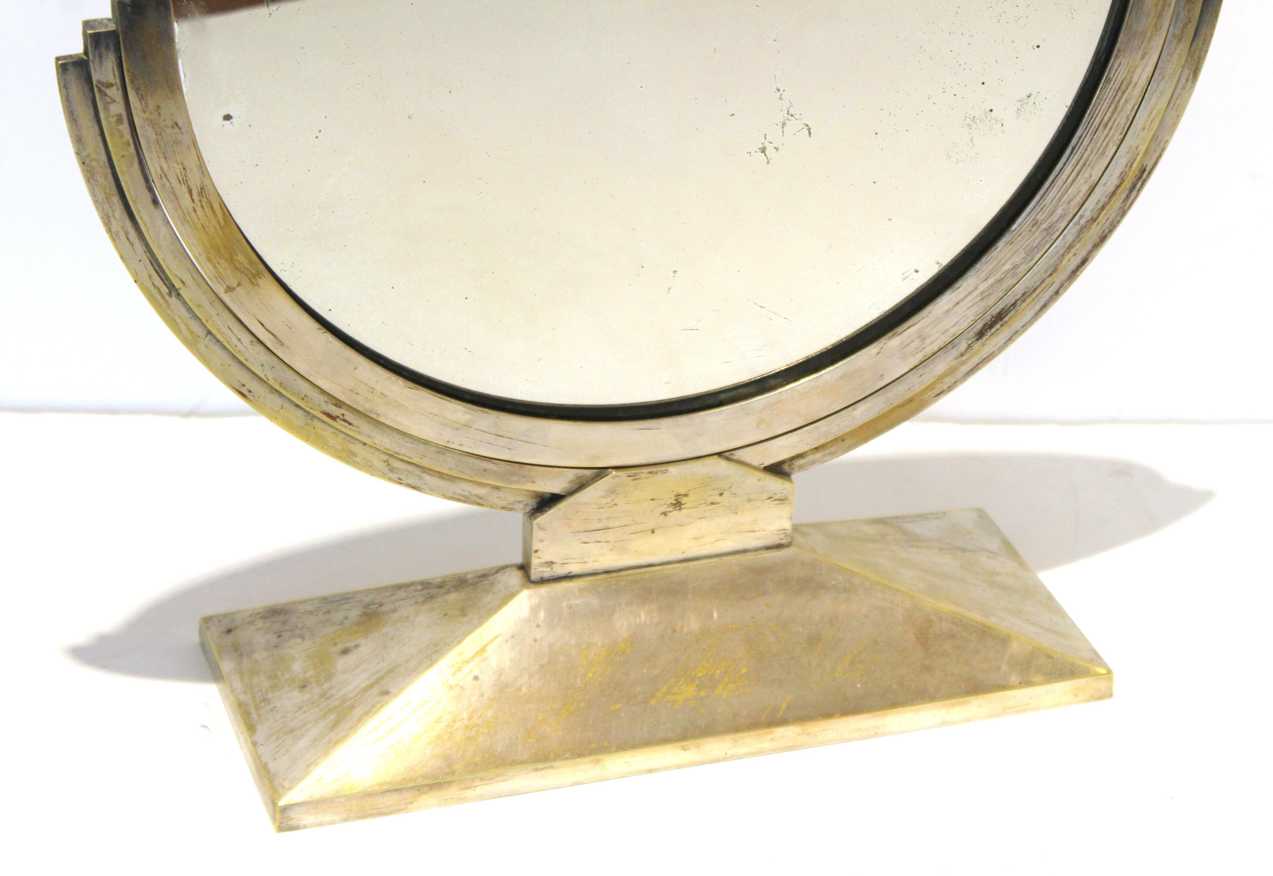 French Art Deco round tabletop mirror or vanity mirror attributed to Maison Desny. The piece has silvered nickel over a bronze structure and pivots. The modernist design gives it a sleek minimal aura. Made in France in the 1920s-1930s, the piece is