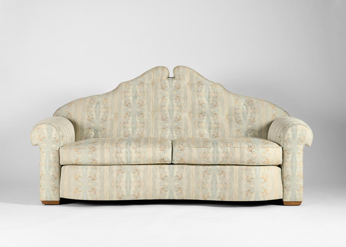 Das brillant gestaltete Sofa aus den 1930er Jahren ist an der Vorderseite geschwungen, wird von zwei großzügigen, geschwungenen Armlehnen gestützt und ist mit einer hohen Rückenlehne gekrönt, die sich von beiden Seiten zu einem hohen zentralen Punkt