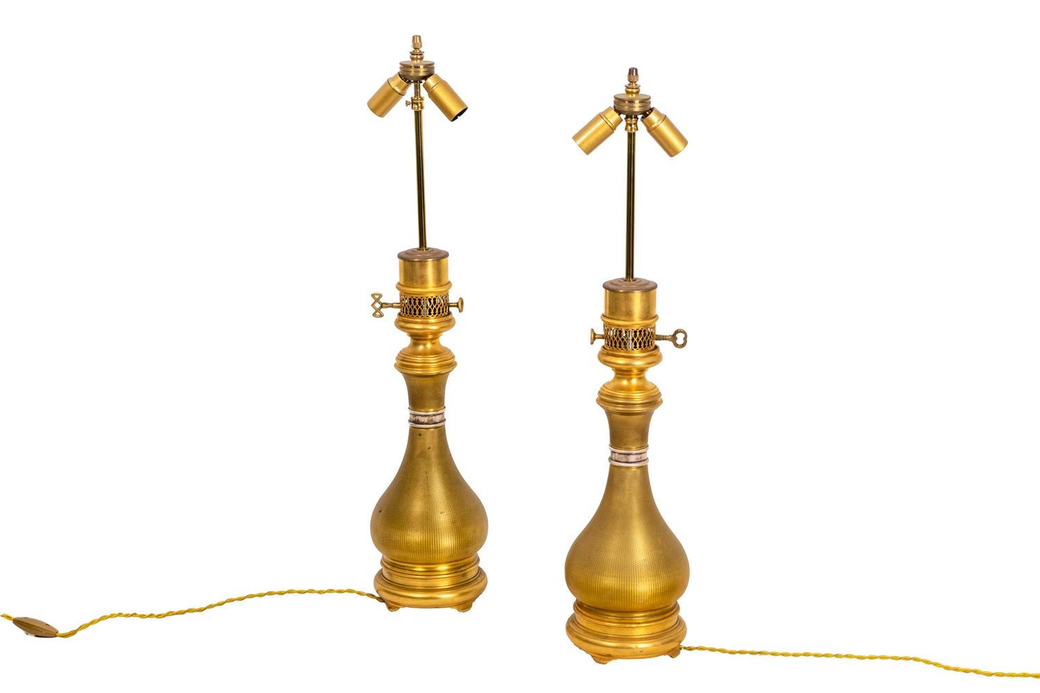 Maison Gagneau, signed.
Pair of baluster shape lamps in guilloche gilt brass. They stand on a circular base. The collar is circled with a silvered ring.

Stamped “Gagneau, 115 R. Lafayette” on the openwork beak.

Work realized in the late 19th