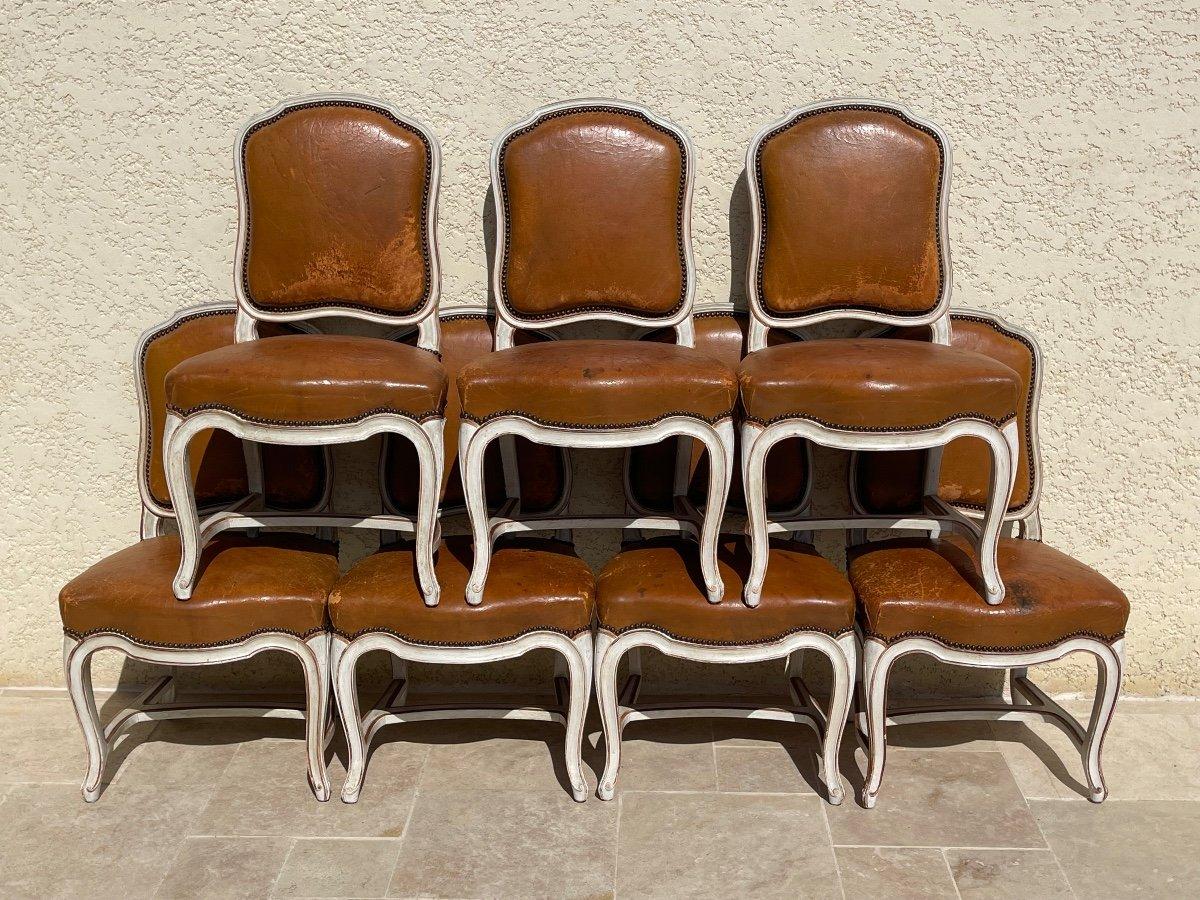 Set of 8 Louis XV style ecru lacquered wood chairs with backs and seats covered in cognac leather. They are in good general condition. The wooden structure is very rigid and the chairs are very stable. Parisian French work from Maison Gouffé. The