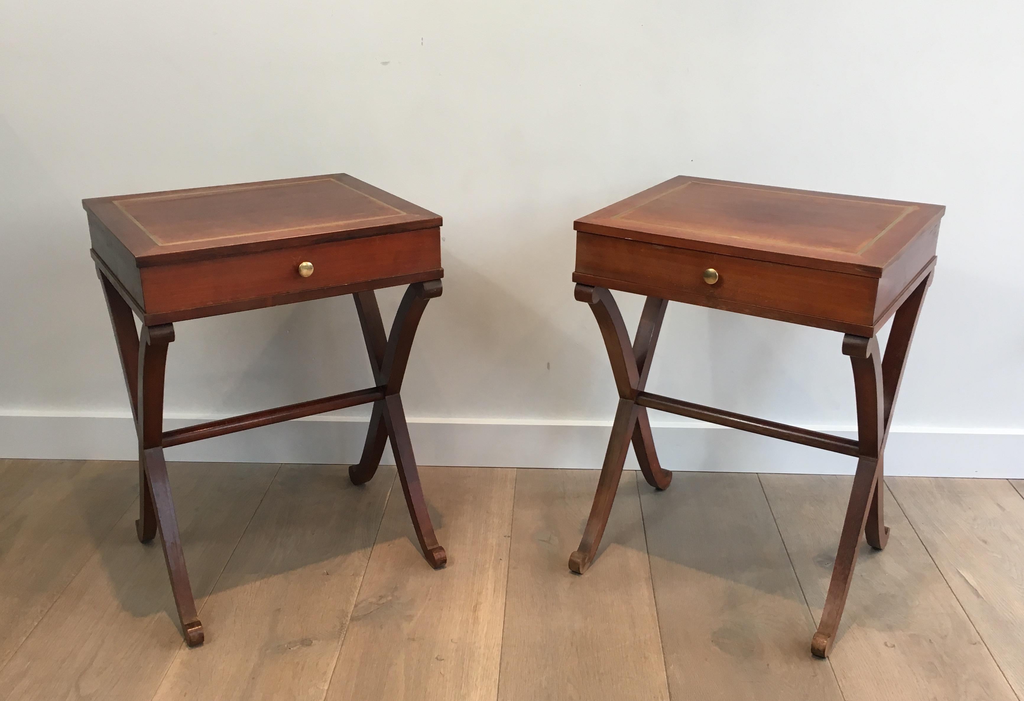 This nice pair of neoclassical side tables is made of mahogany. They have a rounded X base, a drawer and a rectangular brass net on the top part. These end table have been made by famous French designer Maison Hirch, circa 1940. They are signed