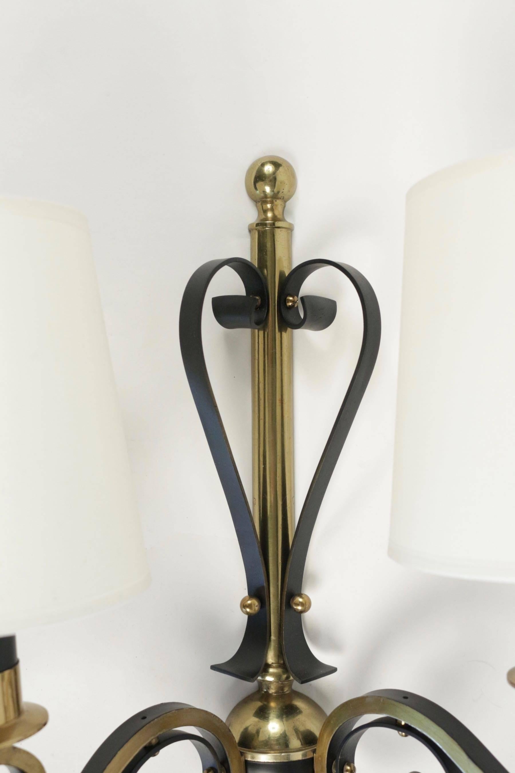 1960s Maison Honoré pair of sconce.
 
The sconces are composed by two lighted arm adorned with volute motif, made of black lacquered wrought iron. The motif is highlighted with brass parts.
black plate made of brass, with a ball at each