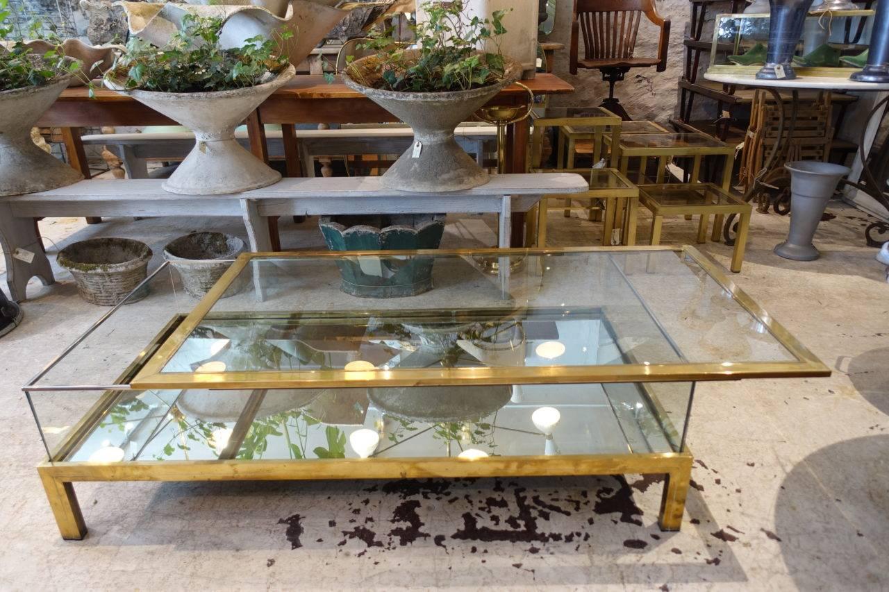 Sophisticated and stunning French coffee table, from the renowned house of interior design, Maison Jansen, circa 1970. Elegantly made with a gorgeous slim brass frame, mirrored base, and refined sliding glass top. Stylish craftsmanship.

Maison