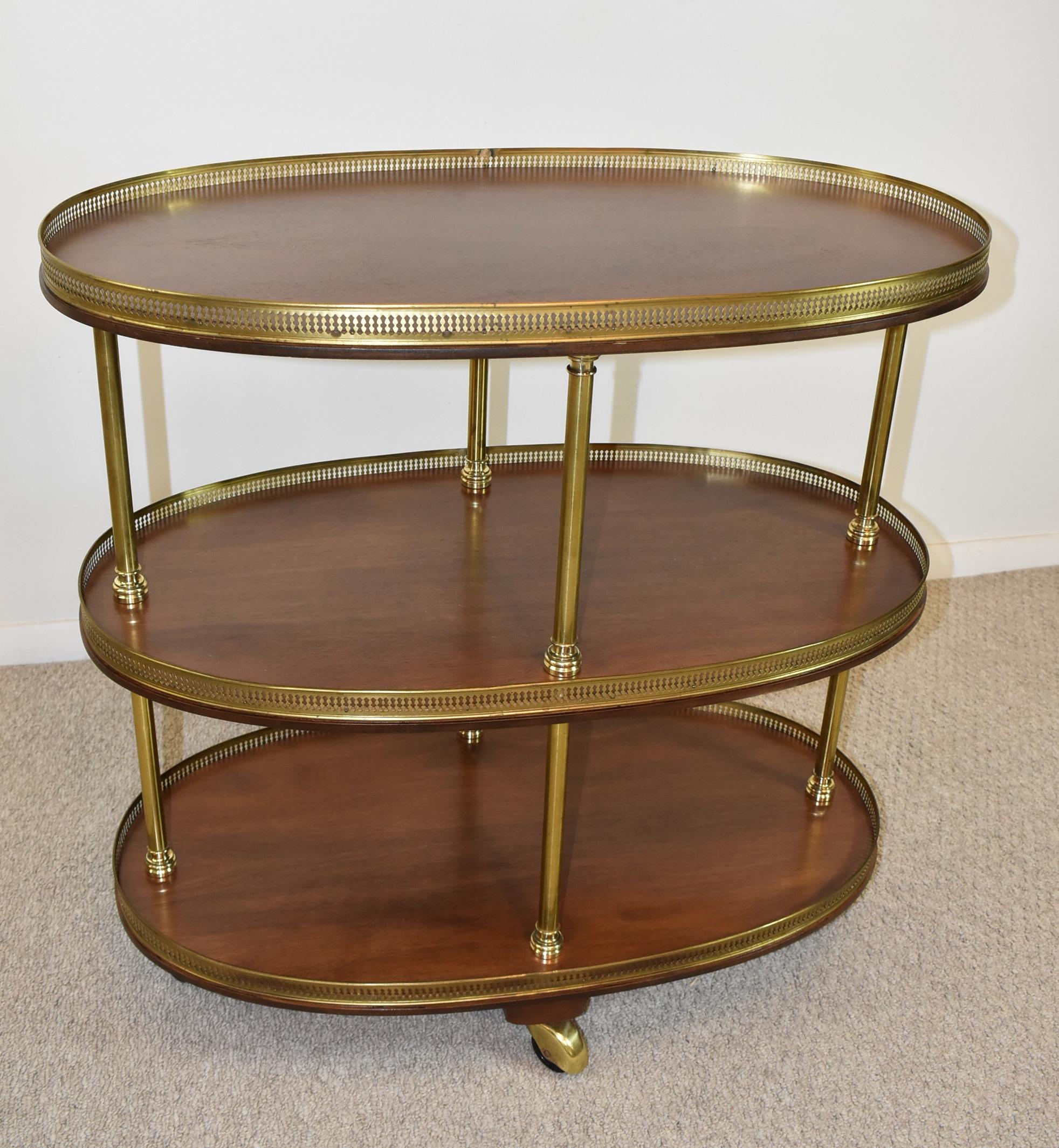 3 tier Maison Jansen Beverage Cart. Each shelf has pierced brass gallery with turned brass pillars and caps. Shelves are refinished walnut. Excellent vintage condition with minor wear to the wheel covers. 11 1/2