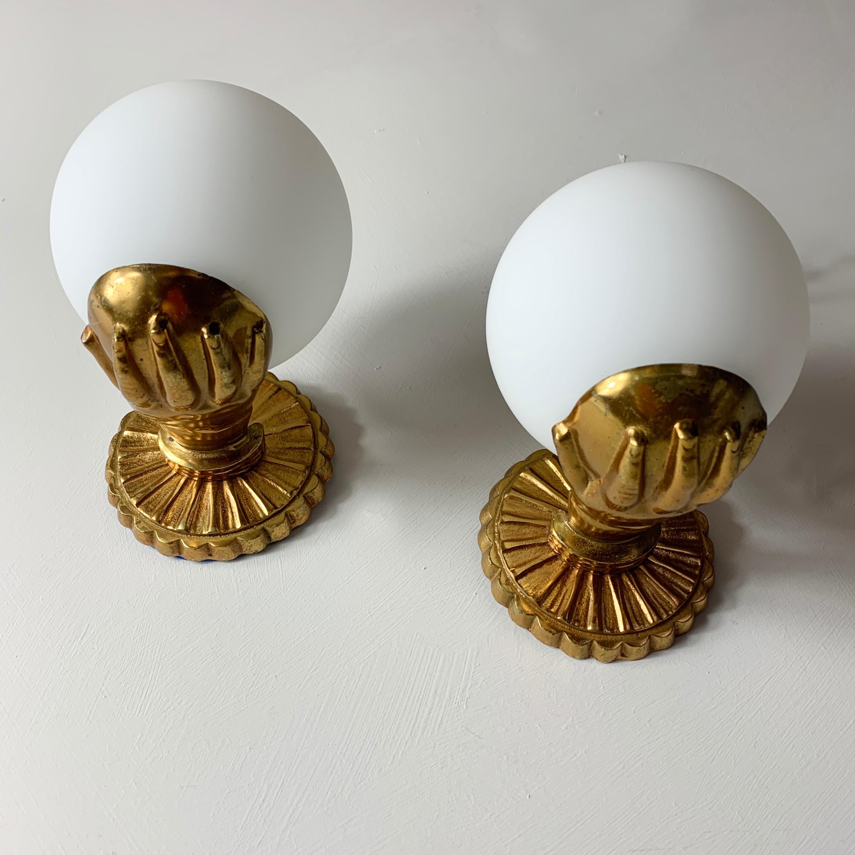 Brass hand and globe wall lights
Attributed to Maison Jansen
France, midcentury
Solid brass hands holding a cup against a scalloped back
Glass globes are modern replacements
13cm depth from wall, 15cm approx height, 10cm width of globe, rose