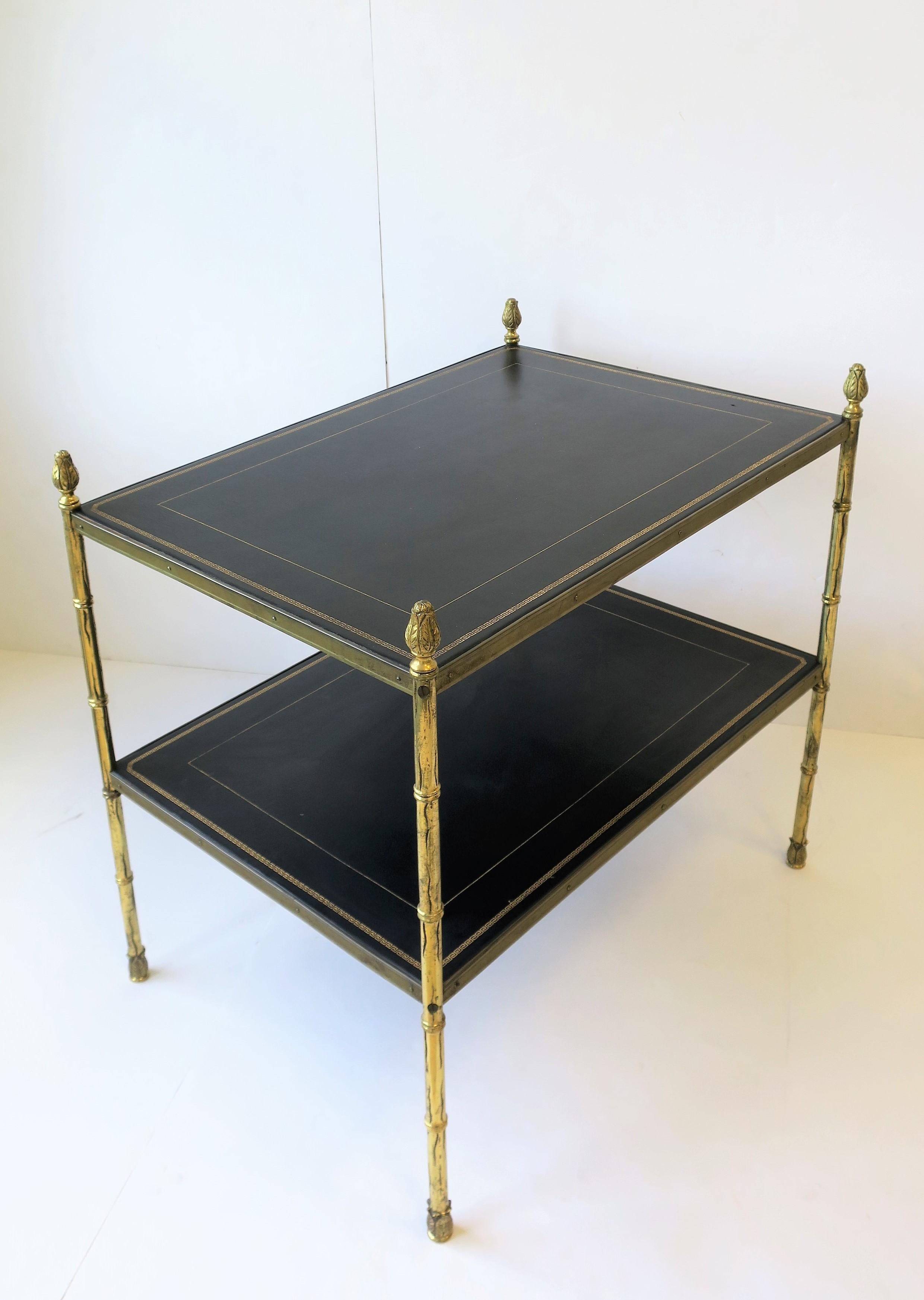 A very beautiful European Maison Jansen attributed rectangular two-tier gold brass and black leather end table in the Empire style, circa mid-20th century, Spain. Table can work as an end table or nightstand table, alternatively, table may also work