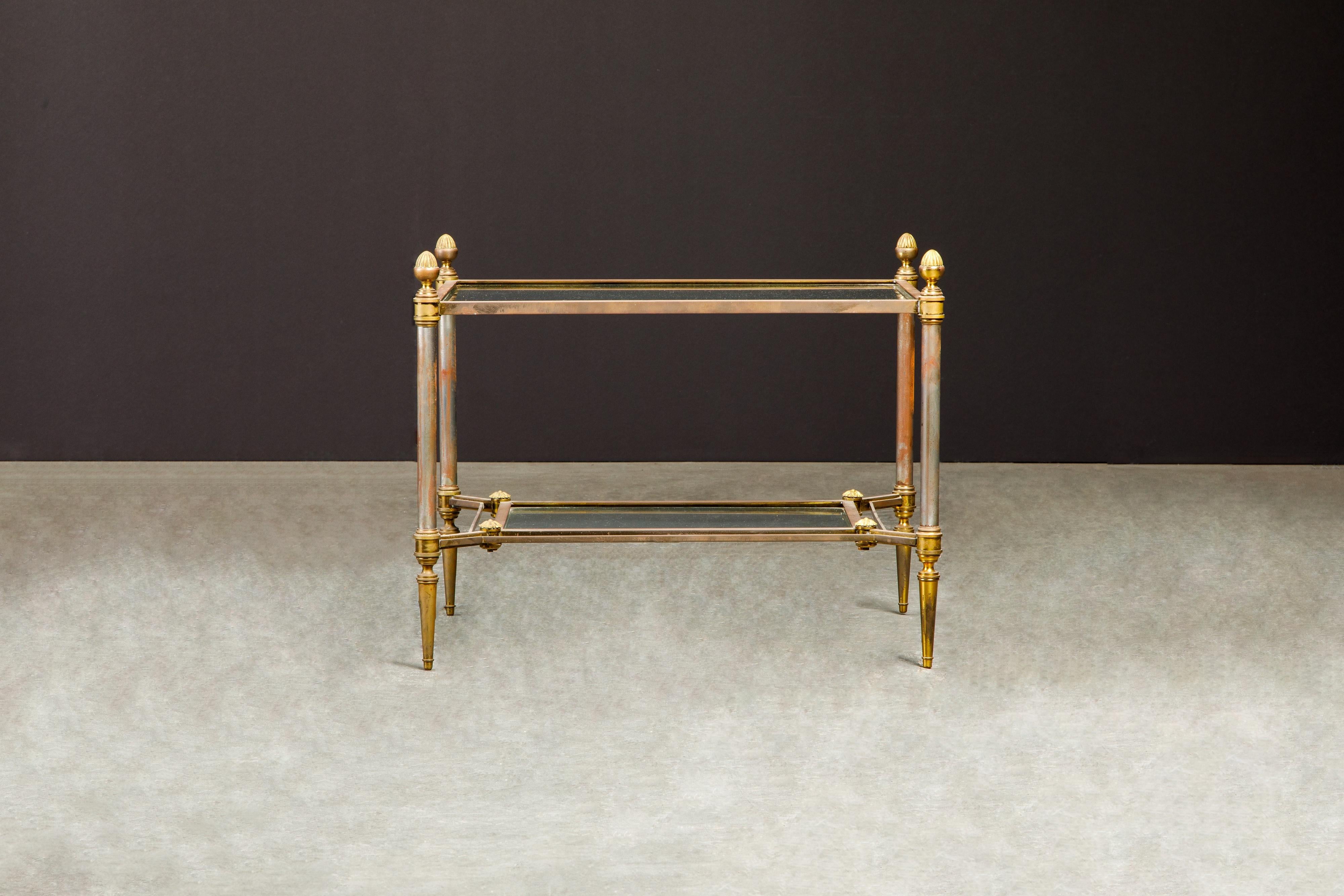 A beautiful brass, steel and glass tiered side table, attributed to Maison Jansen circa 1960, has plenty of patina developed over years which is attractive in of itself, or can be polished to remove this patina if desired. 

This attractive Jansen