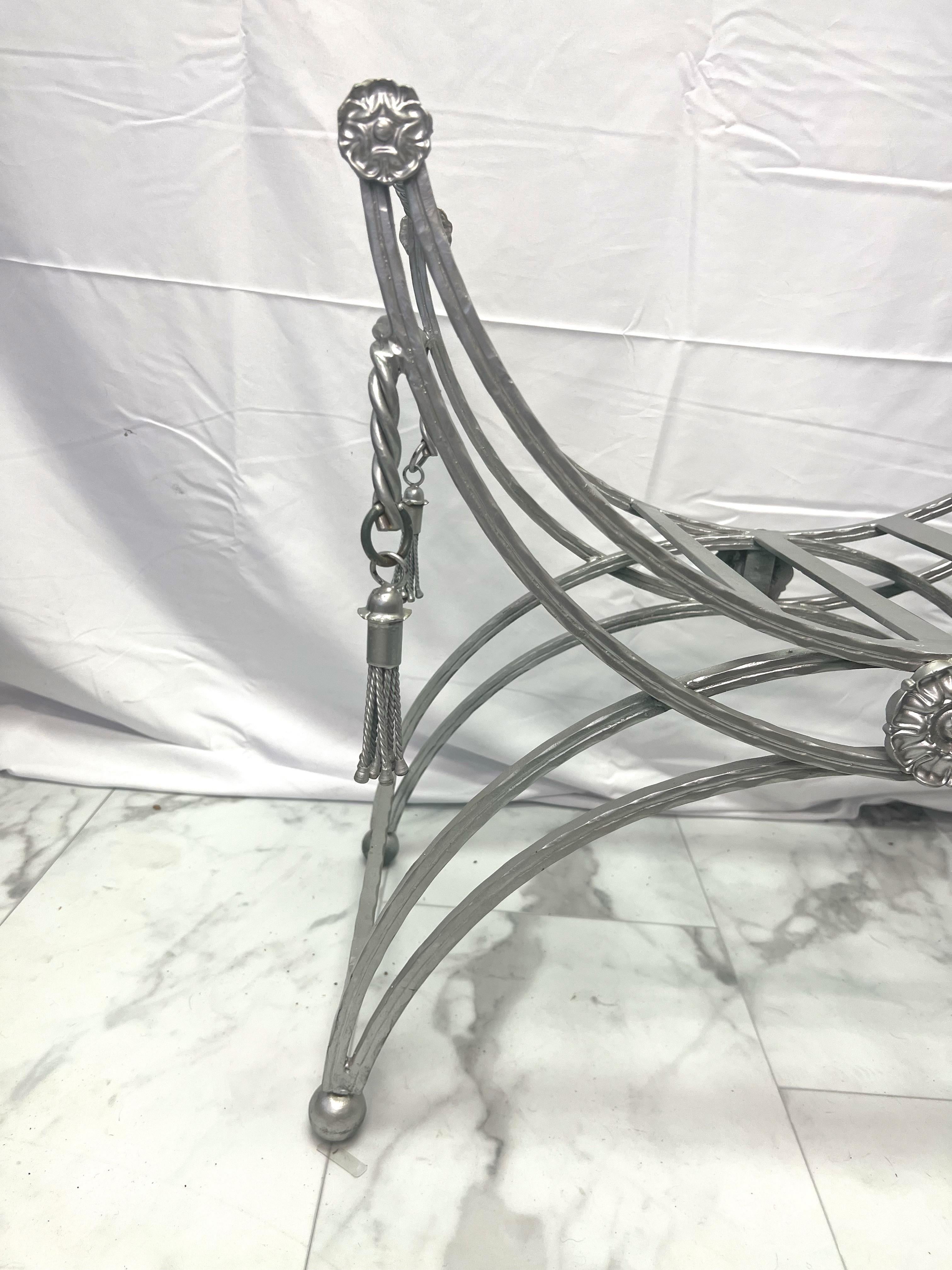 Very heavy iron or steel bench attributed to Maison Jansen.  French Mid-Century steel frame vanity stool with   metal rope and tassels on all 4 corners and metal rosette’s adorning the stool. with attached curved legs ending in ball finials, and a