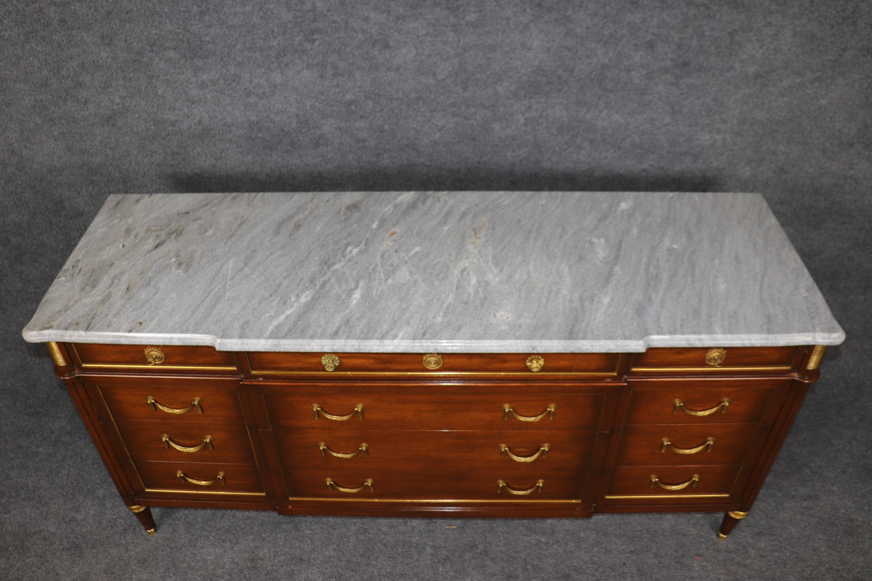 Il s'agit d'une magnifique commode triple de la plus haute qualité attribuée à la Maison Jansen. Le marbre gris est absolument magnifique et en bon état d'origine. La caisse est ornée de montures en laiton et en bronze et de certaines des plus